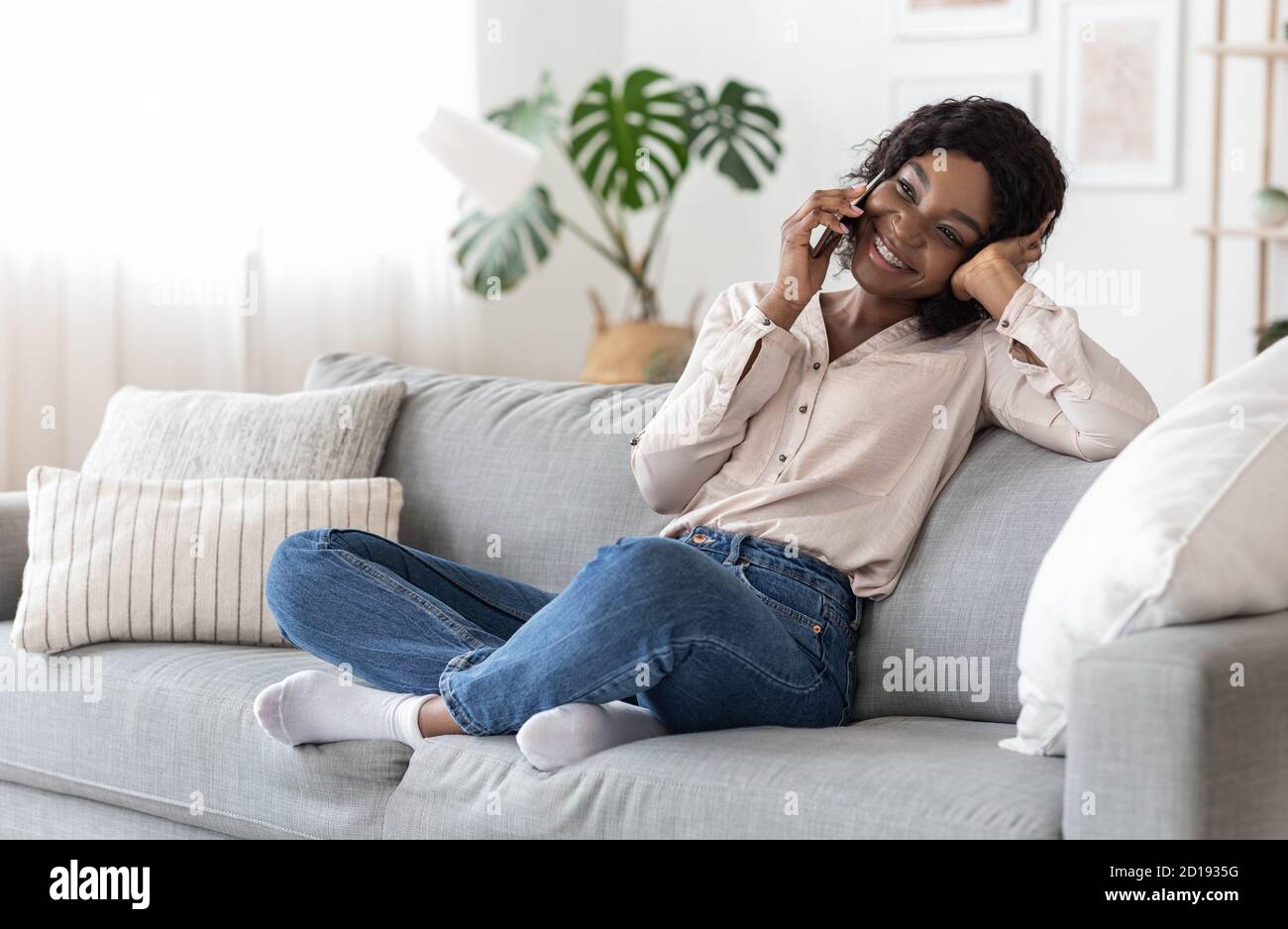 Mobile Kommunikation. Fröhliche afrikanische Frau im Gespräch auf Handy mit Freunden zu Hause Stockfoto
