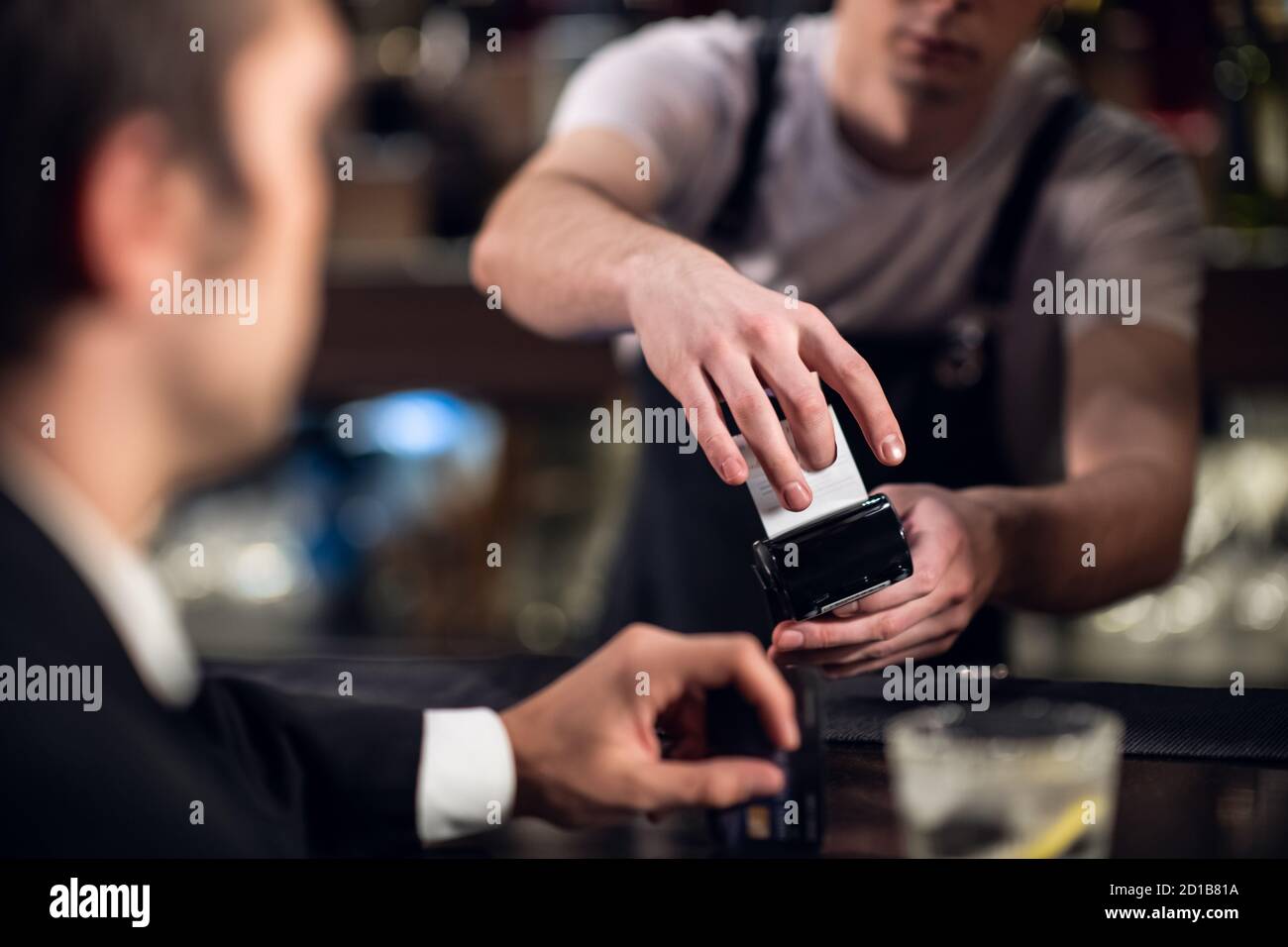 Der Mann bezahlt den Barkeeper für die Bestellung mit einer Kreditkarte. Stockfoto