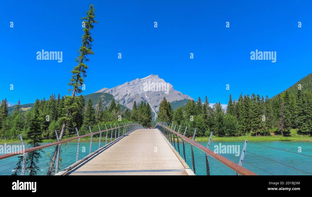 Banff Stadt in Alberta, Kanada. Der Blick auf die Brücke über den türkisfarbenen Bow River. Kiefernwälder / Wald und Mount Rundle im Hintergrund. Stockfoto