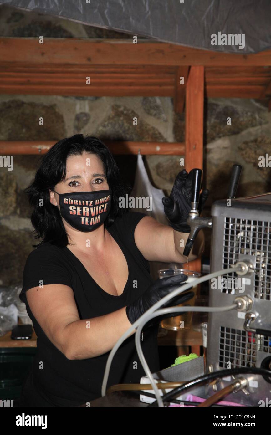 Eine kellnerin zapft bier während einer veranstaltung in der corona pandemie, mund nasen schutz maske Stockfoto