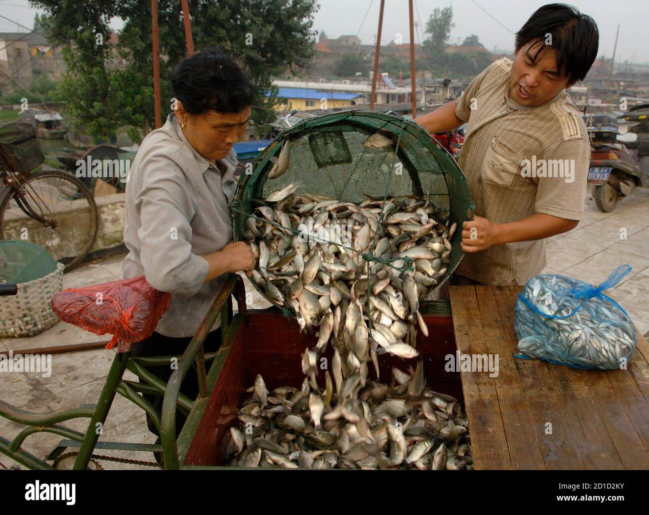 Ein Großhändler (L) kauft Fisch vom Fischer an einem Dock in Huai'an, Provinz Jiangsu 5. August 2007. Globaler Zusammenarbeit ist die einzige Möglichkeit zur Verbesserung der Lebensmittelsicherheit, chinesischen offizielle Medien sagte am Sonntag nach noch eine weitere Woche der weltweiten Angst über die Qualität der Ware aus China. REUTERS/Patty Chen (CHINA) Stockfoto