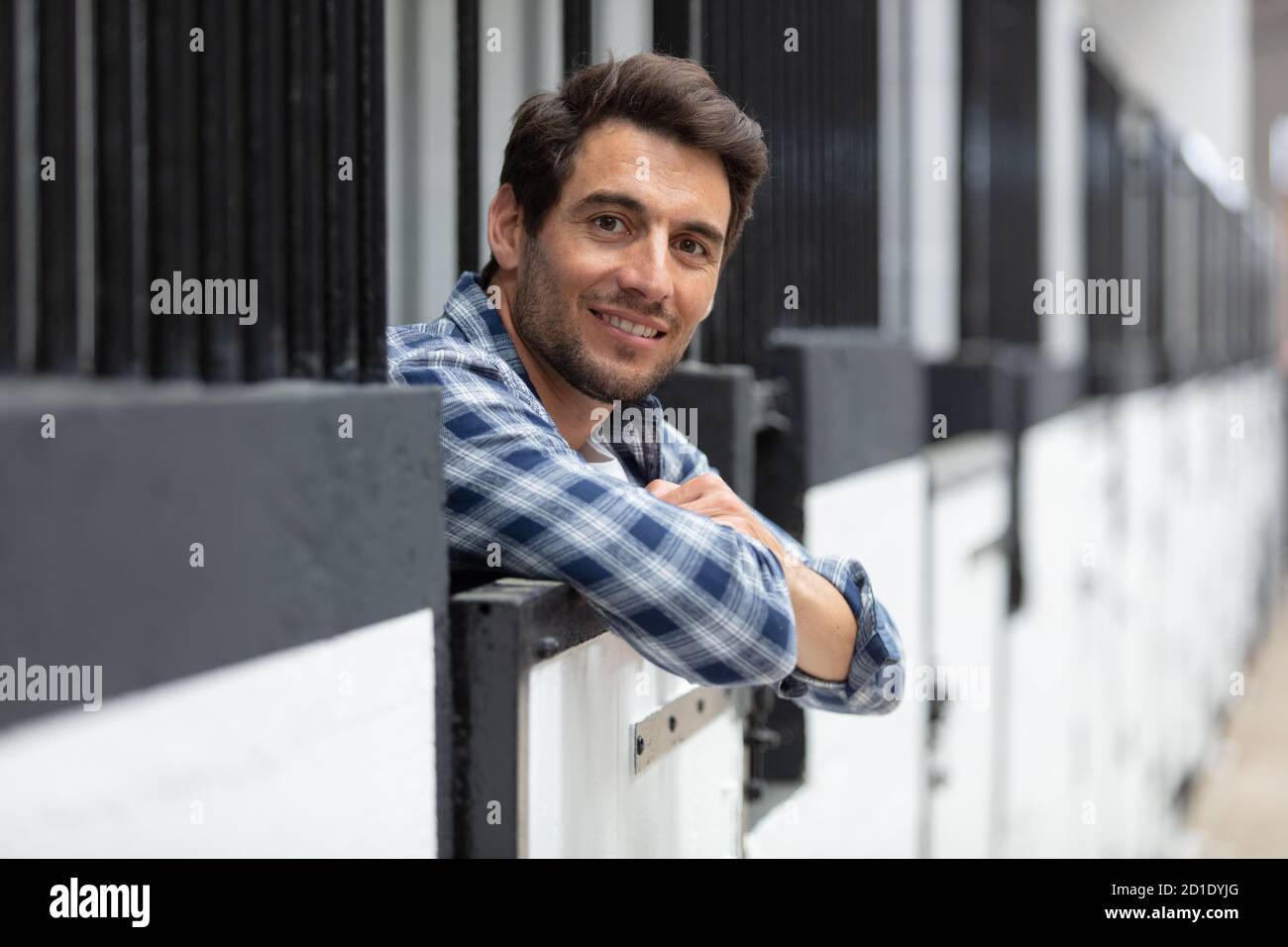 Glücklich lächelnder junger Mann in Kuhstall auf Milchviehbetrieb Stockfoto