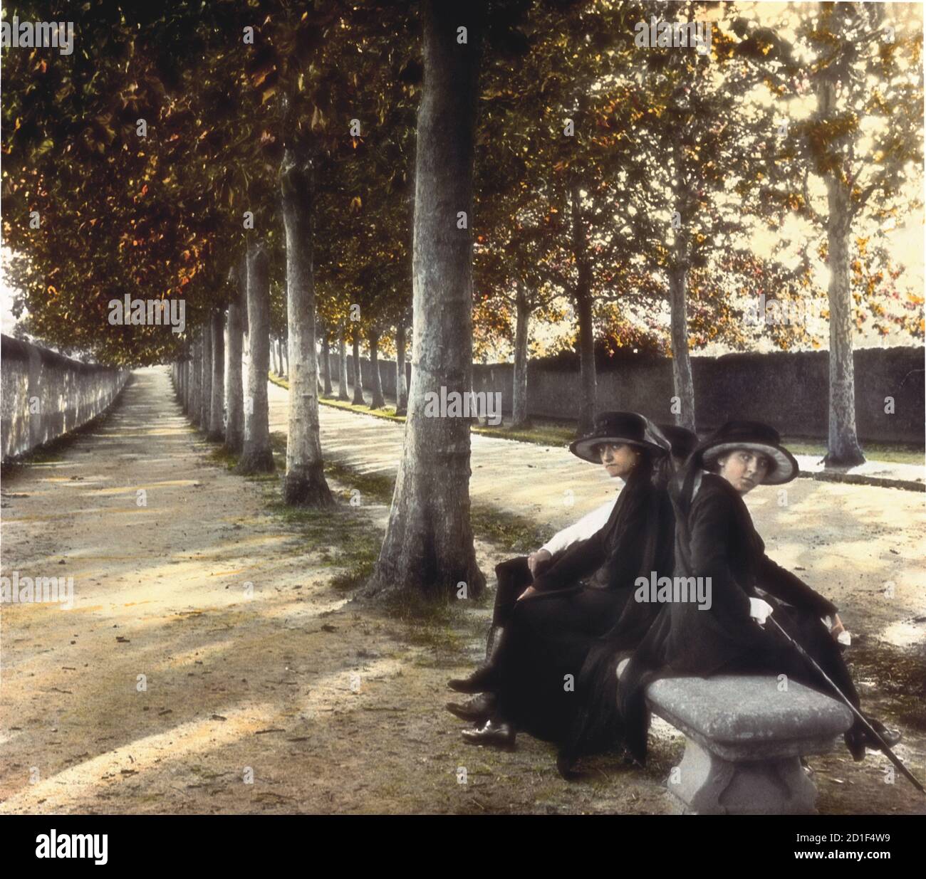 Koloriertes Foto von zwei Frauen, die auf einer Bank an einem baumgesäumten Boulevard sitzen, Paris, Frankreich, 1910. (Foto von Burton Holmes) Stockfoto