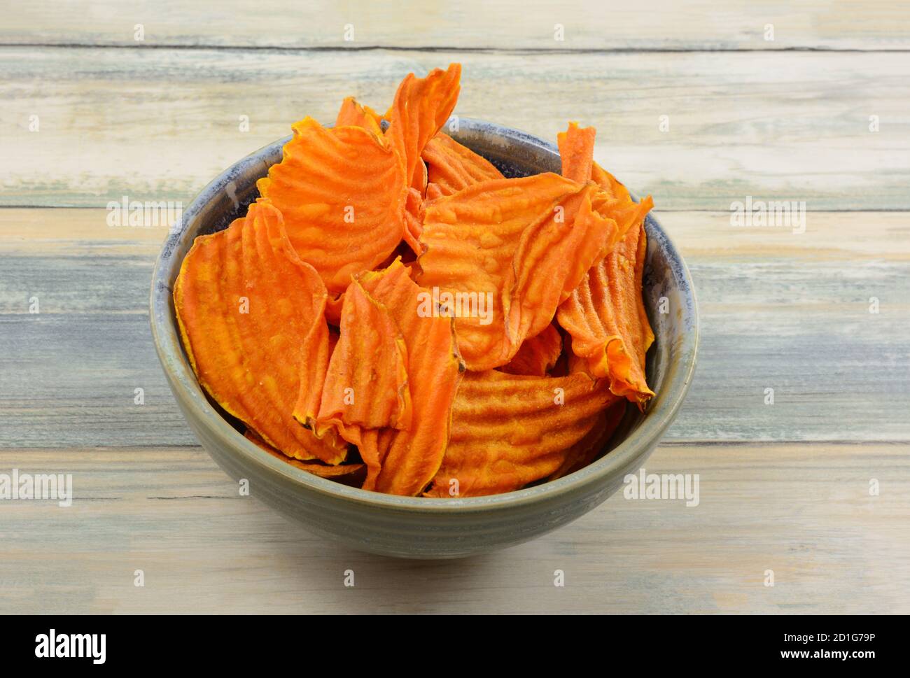 Bio-Süßkartoffelchips in Keramik-Snack-Schale auf dem Tisch Stockfoto