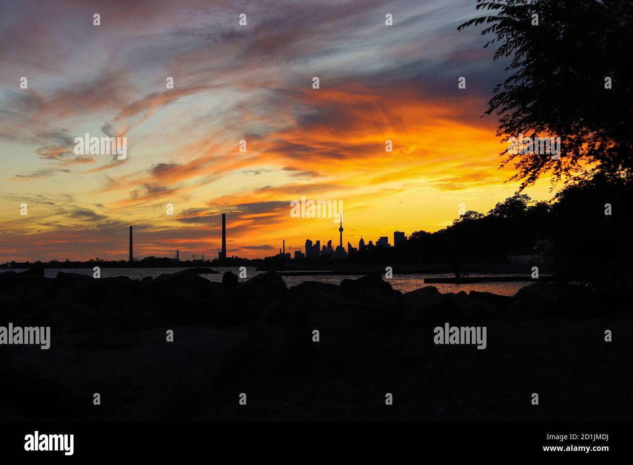 Sonnenuntergang in der Stadt. Dunkelheit Stadtbild und goldene Stunde. Blaue und gelbe Farben bewölkten Himmel und See Stockfoto