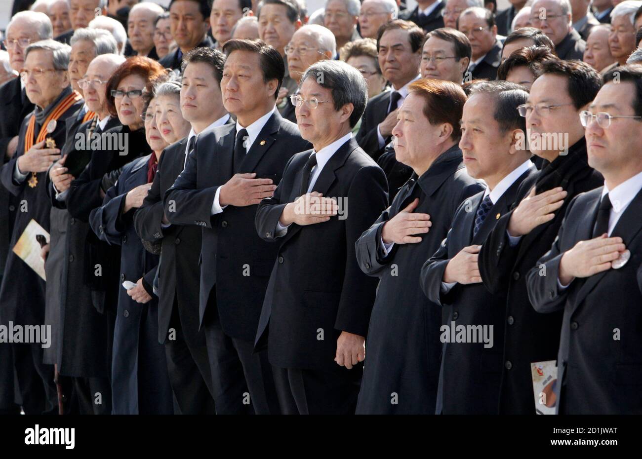 Der südkoreanische Premierminister Chung UN-chan (5. R, erste Reihe), Regierungsbeamte und Bürger begrüssen die Nationalflagge bei einer Zeremonie auf der Seoul City Hall Plaza am 26. März 2010, um des 100. Jahrestages der Hinrichtung des koreanischen Unabhängigkeitskämpfers Ahn Jung-geun durch Japan zu gedenken. Ahn war der Mann, der im Oktober 1909 in Chinas nordöstlicher Stadt Harbin Hirobumi Ito, den ersten japanischen General in Korea, erschossen hat. Japan hatte die koreanische Halbinsel zwischen 1910 und 1945 gewaltsam besetzt und kolonisiert. REUTERS/Jo Yong-Hak (SÜDKOREA - Tags: JUBILÄUMSPOLITIK) Stockfoto