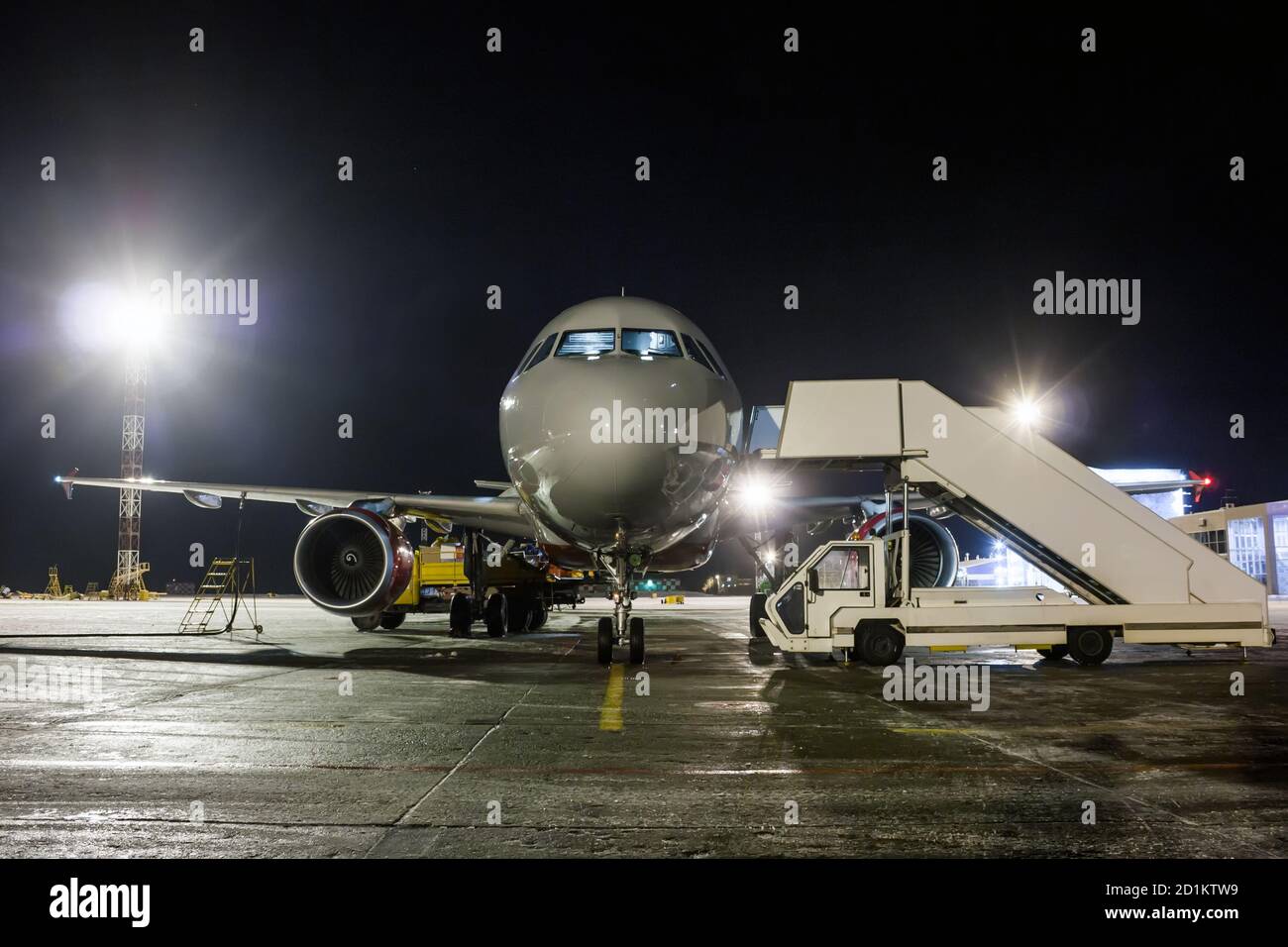 Vorderansicht des Passagierflugzeugs mit Bodenabfertigung bei Nacht Stockfoto
