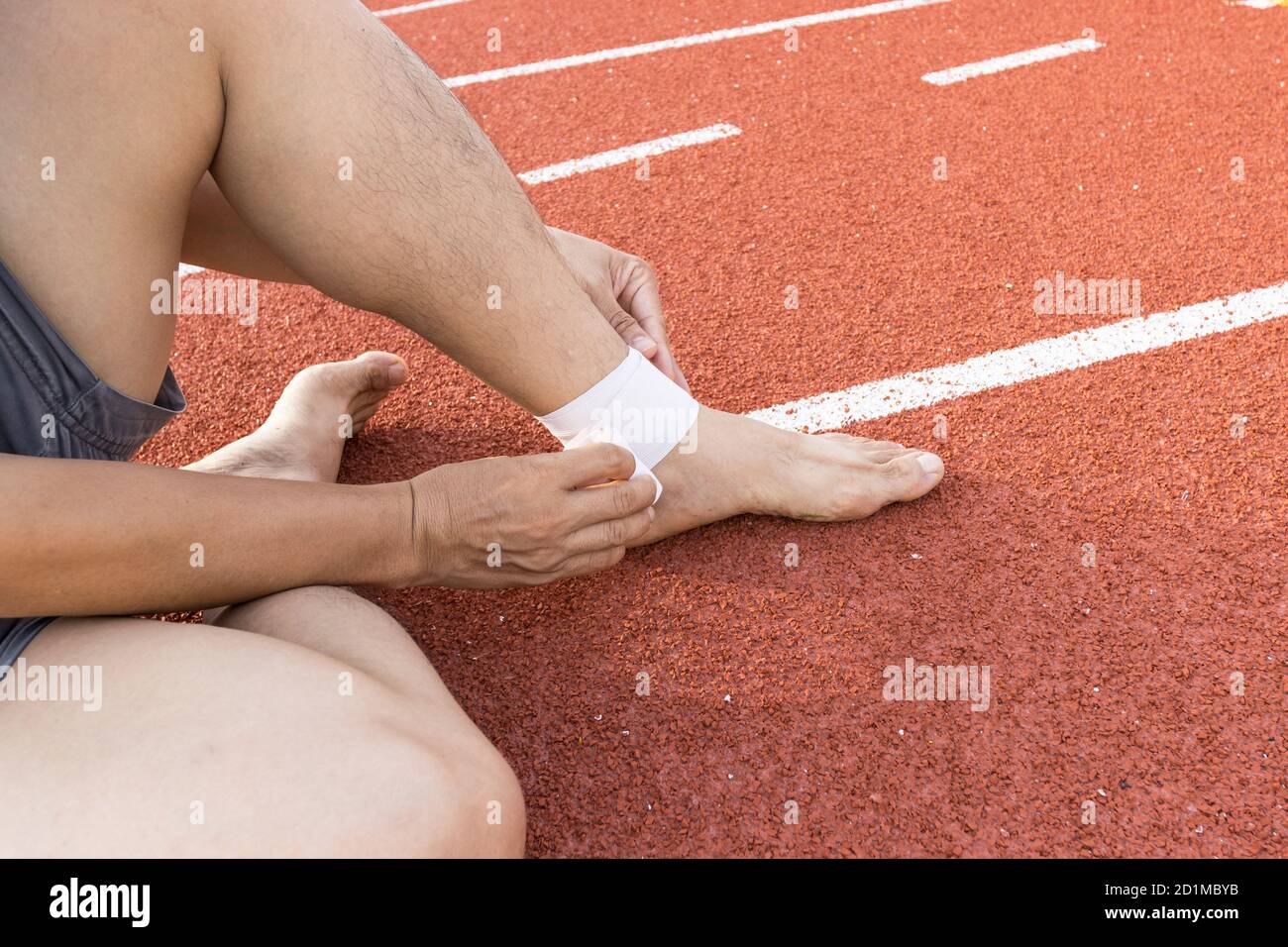 Mann, der Kompressionsbandage auf Knöchelverletzung anwendet nach dem Übungskonzept Sportverletzungen. Stockfoto