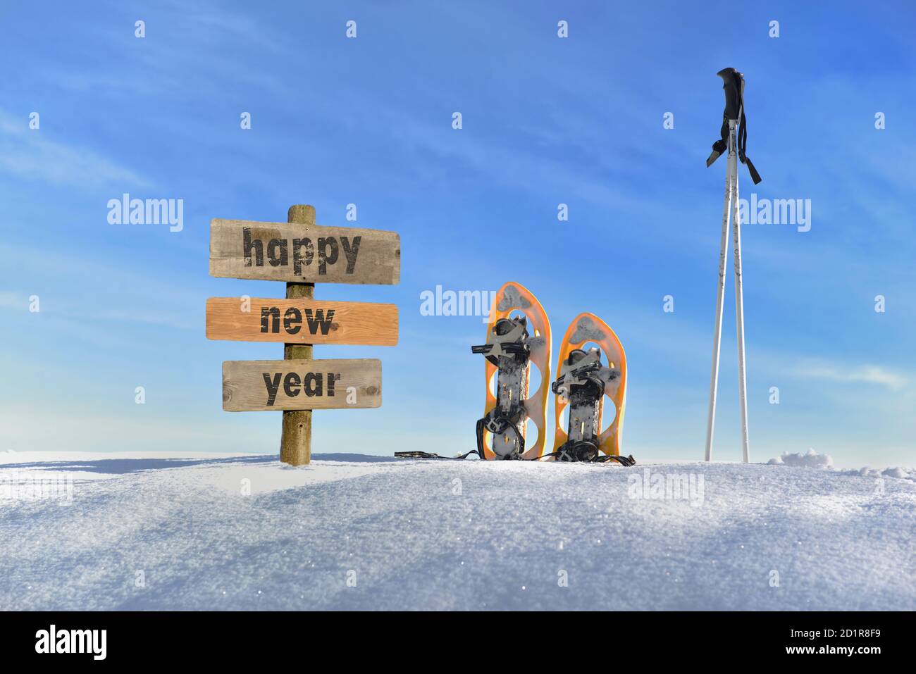 Holzschild mit Text glückliches neues Jahr im Schnee Neben Schneeschuhen und Skisticks Stockfoto