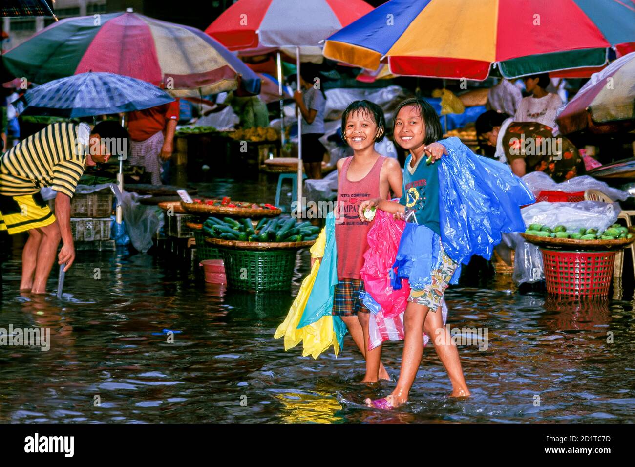 Junge Mädchen, die im Regen durch überflutete Straßen in Manila auf den Philippinen spazieren Stockfoto