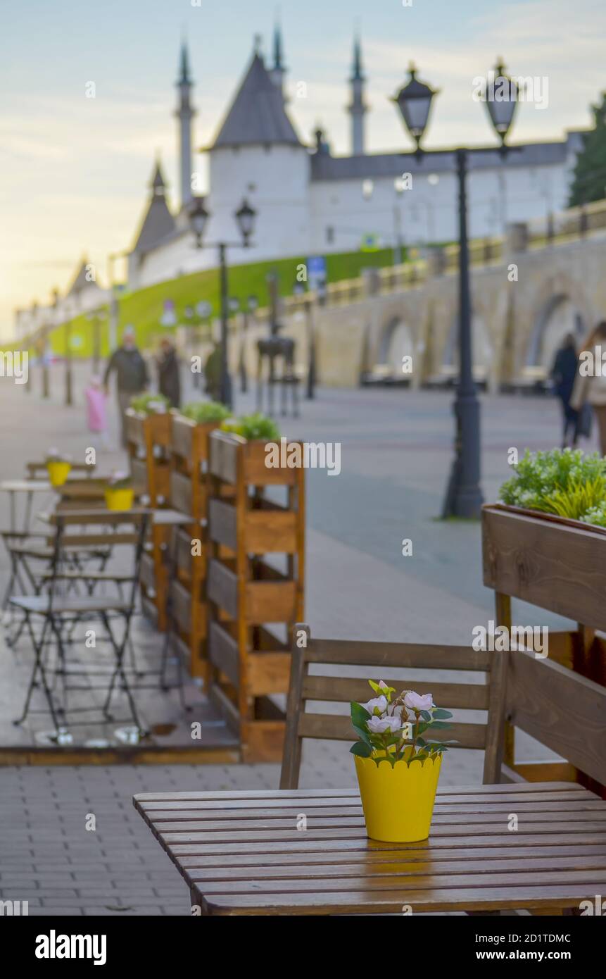 Street Café-Tische mit gelben Blumentöpfen in der Nähe der Wände des Kasan Kreml in Russland, selektive Fokus. Touristische Attraktionen. Stockfoto