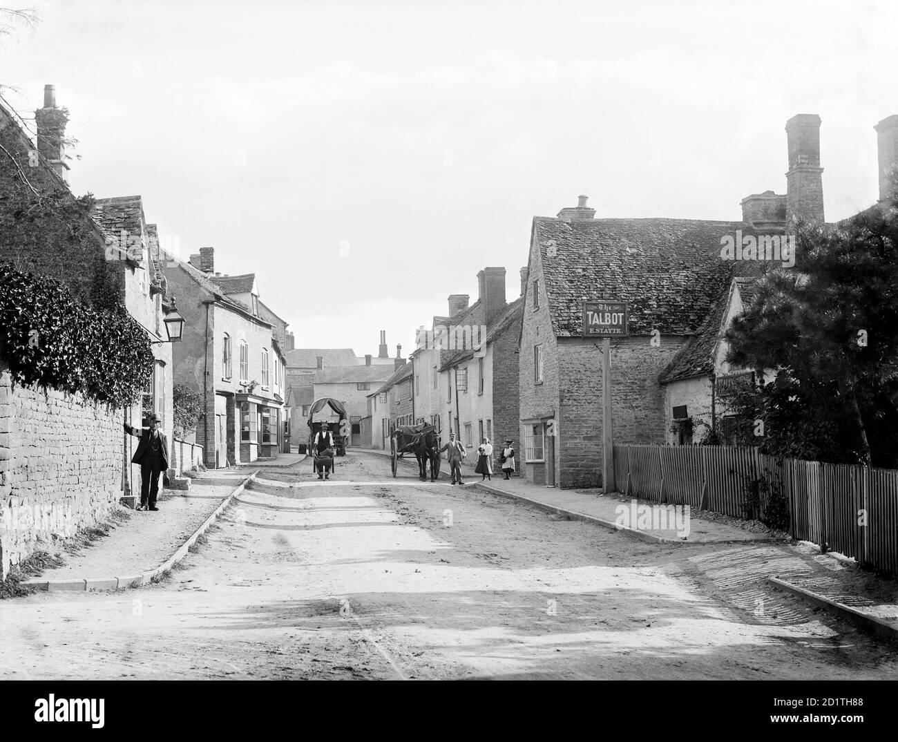 CHARLBURY, Oxfordshire. Eine Straßenszene, die die Thames Street mit mehreren Einwohnern zeigt, einer mit einer Schubkarre, die in der Nähe des öffentlichen Hauses Talbot steht. Fotografiert von Henry Taunt (aktiv 1860 - 1922). Stockfoto