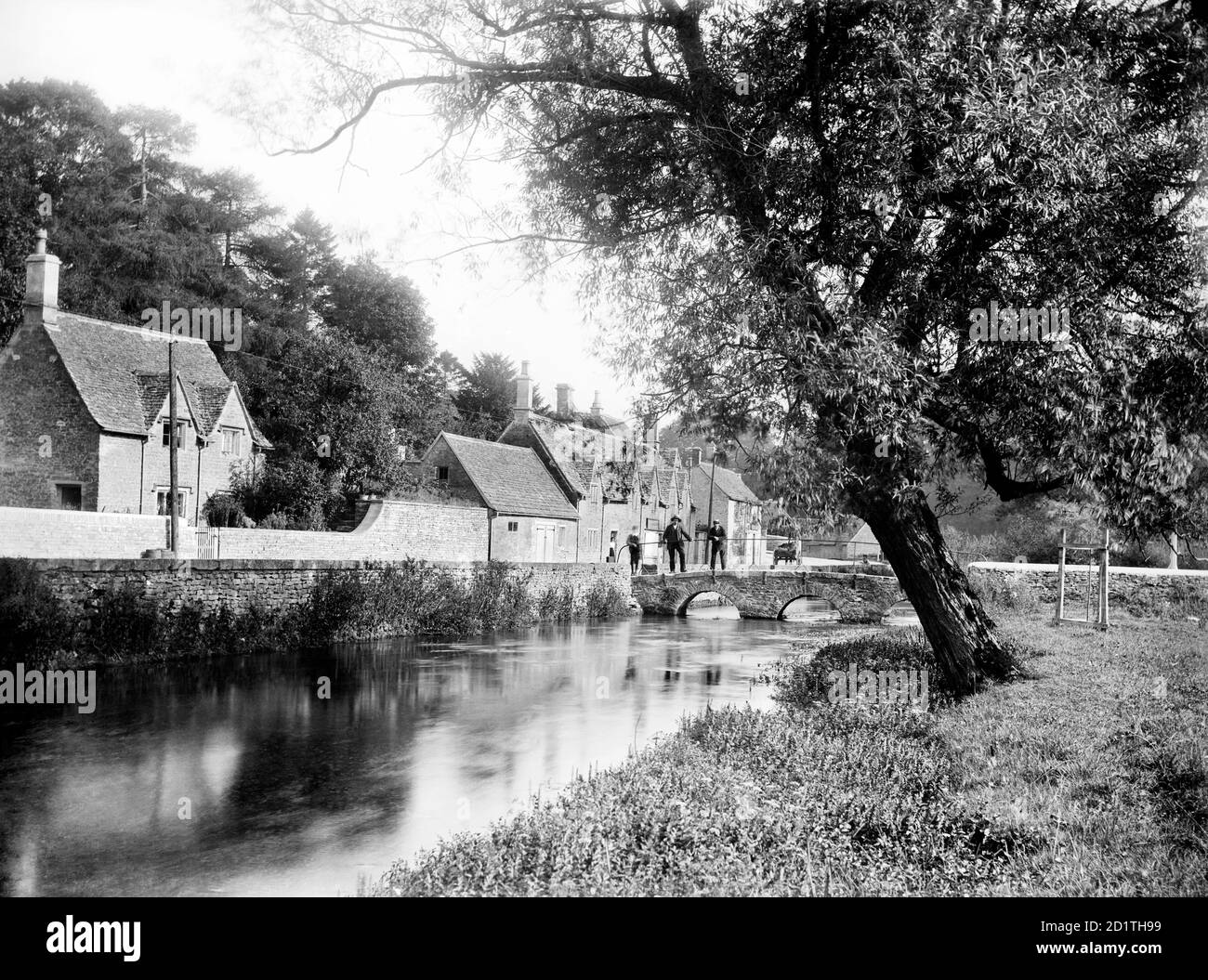 BIBURY, Gloucestershire. Blick entlang des Flusses in Richtung der Steinbrücke neben Arlington Row. Das Cotswold-Dorf Bibury wurde von William Morris als das schönste Dorf Englands bezeichnet. Fotografiert 1906 von Henry Taunt. Stockfoto