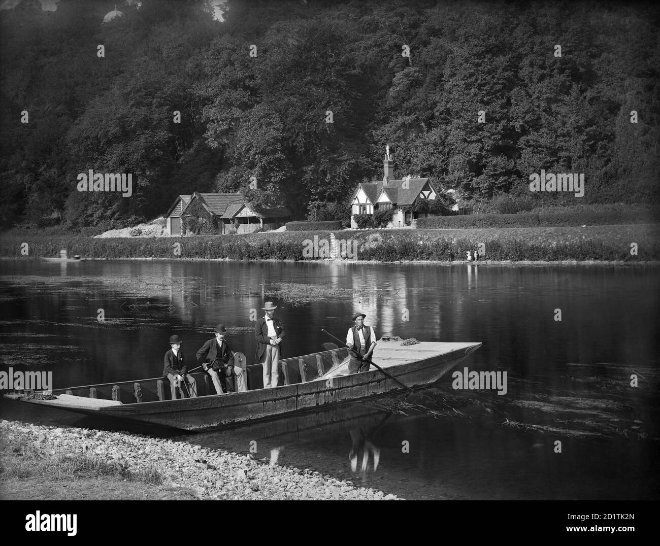 CLIVEDEN FERRY, Cliveden, Taplow, Buckinghamshire. Der Fährmann ist bereit, zwei Männer und einen Jungen über den Fluss zu bringen. Der Mann, der auf der Seite des Bootes sitzt, hält eine Kamera. Die Themse ist an dieser Stelle breit und flach. Henry Taunt, 1885. Stockfoto