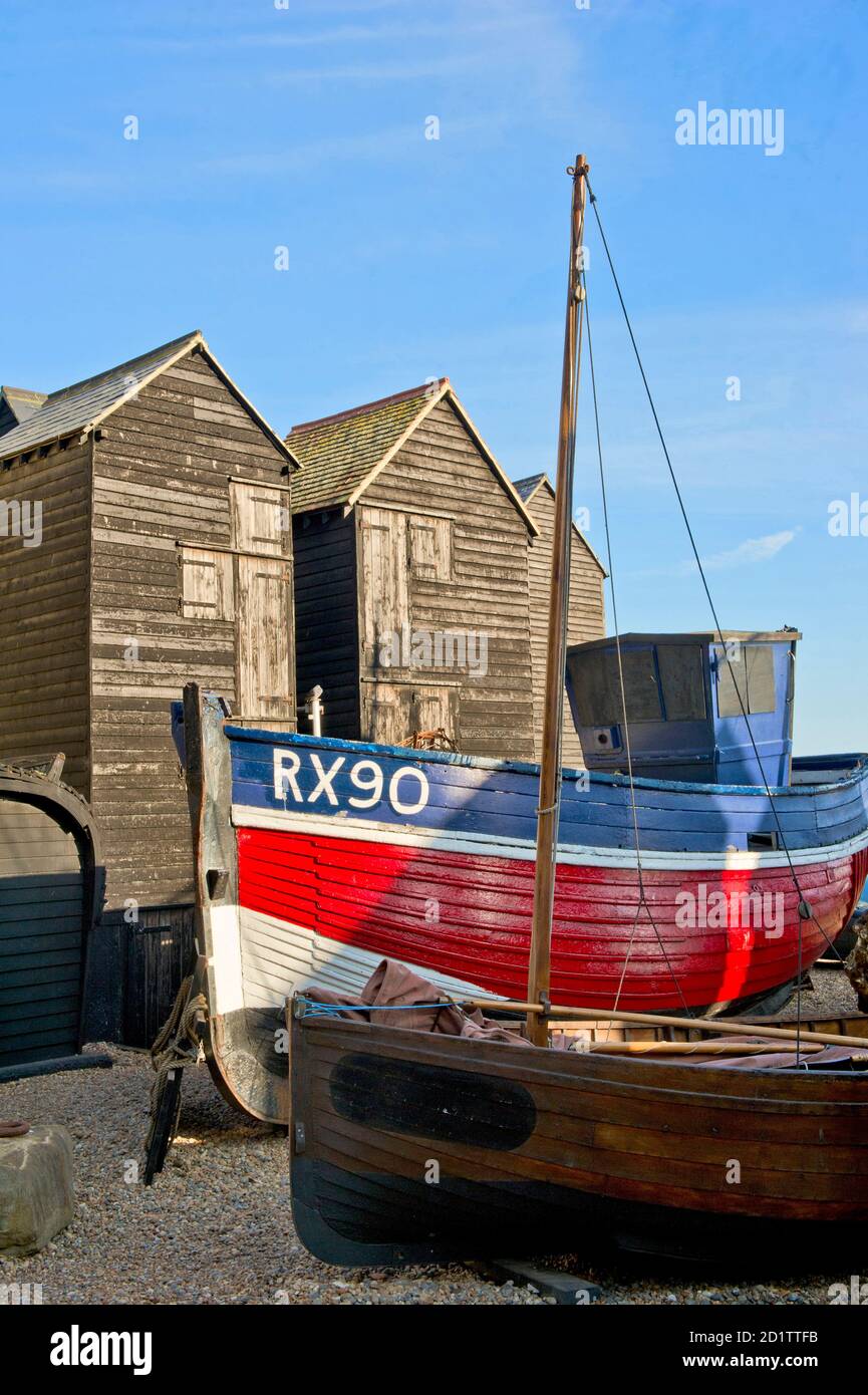 HASTINGS, East Sussex. Ein Trawler liegt am Strand, vor der Strandpromenade "net Shops" angesiedelt. Stockfoto