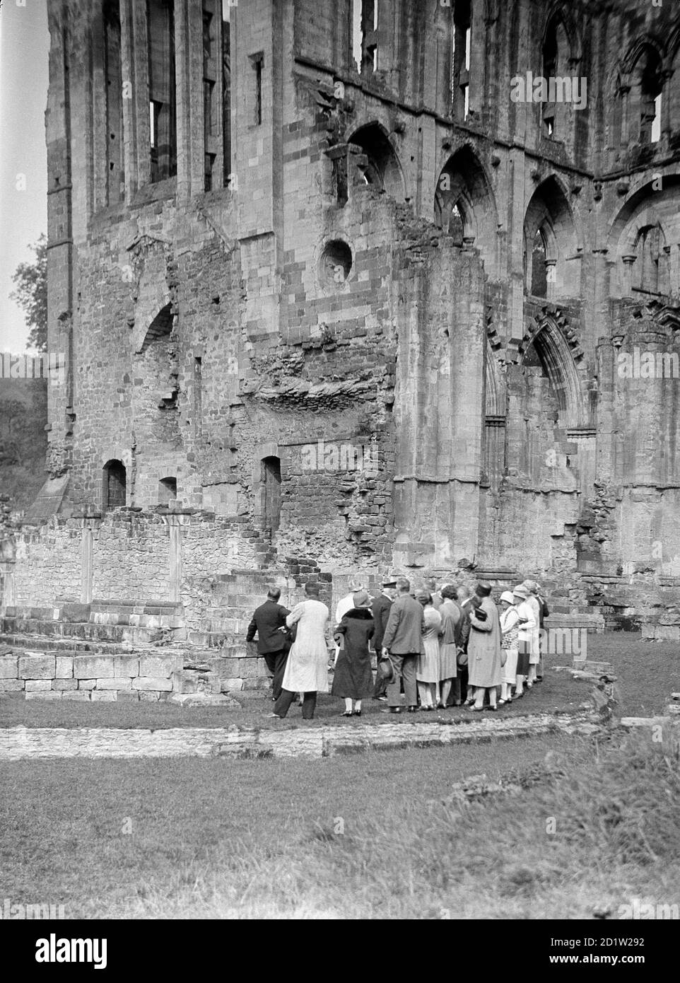 Eine Gruppe von Besuchern, die die Südseite der Abtei von Rievaulx, Rievaulx, North Yorkshire, Großbritannien, betrachten. Stockfoto