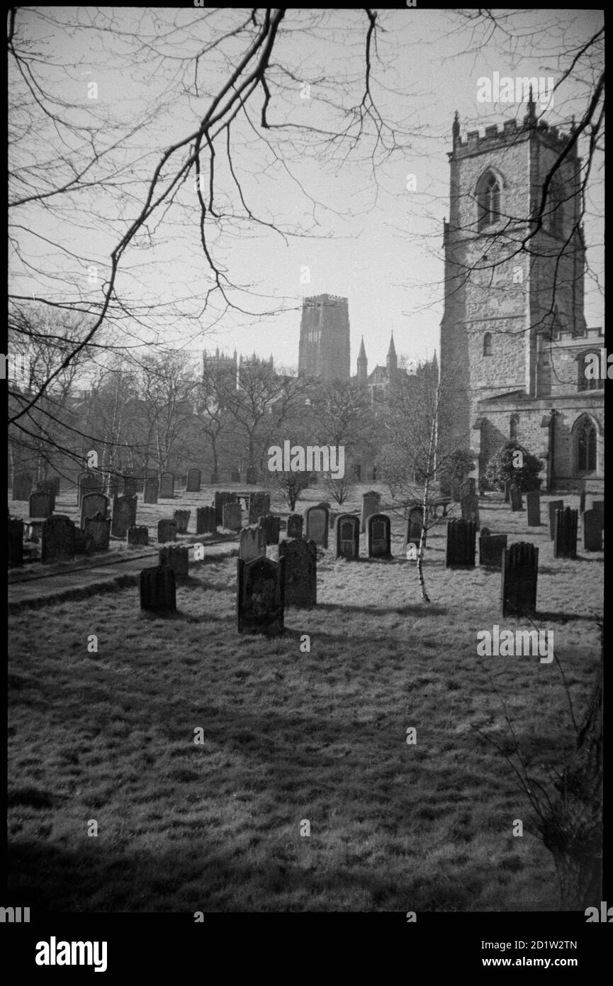 Außenansicht des Westturms der St. Oswald's Church mit Blick nach Nordwesten auf die Christ und die St. Mary the Virgin's Cathedral Church, vom St. Oswald's Friedhof aus gesehen, Grafschaft Durham, Großbritannien. Stockfoto