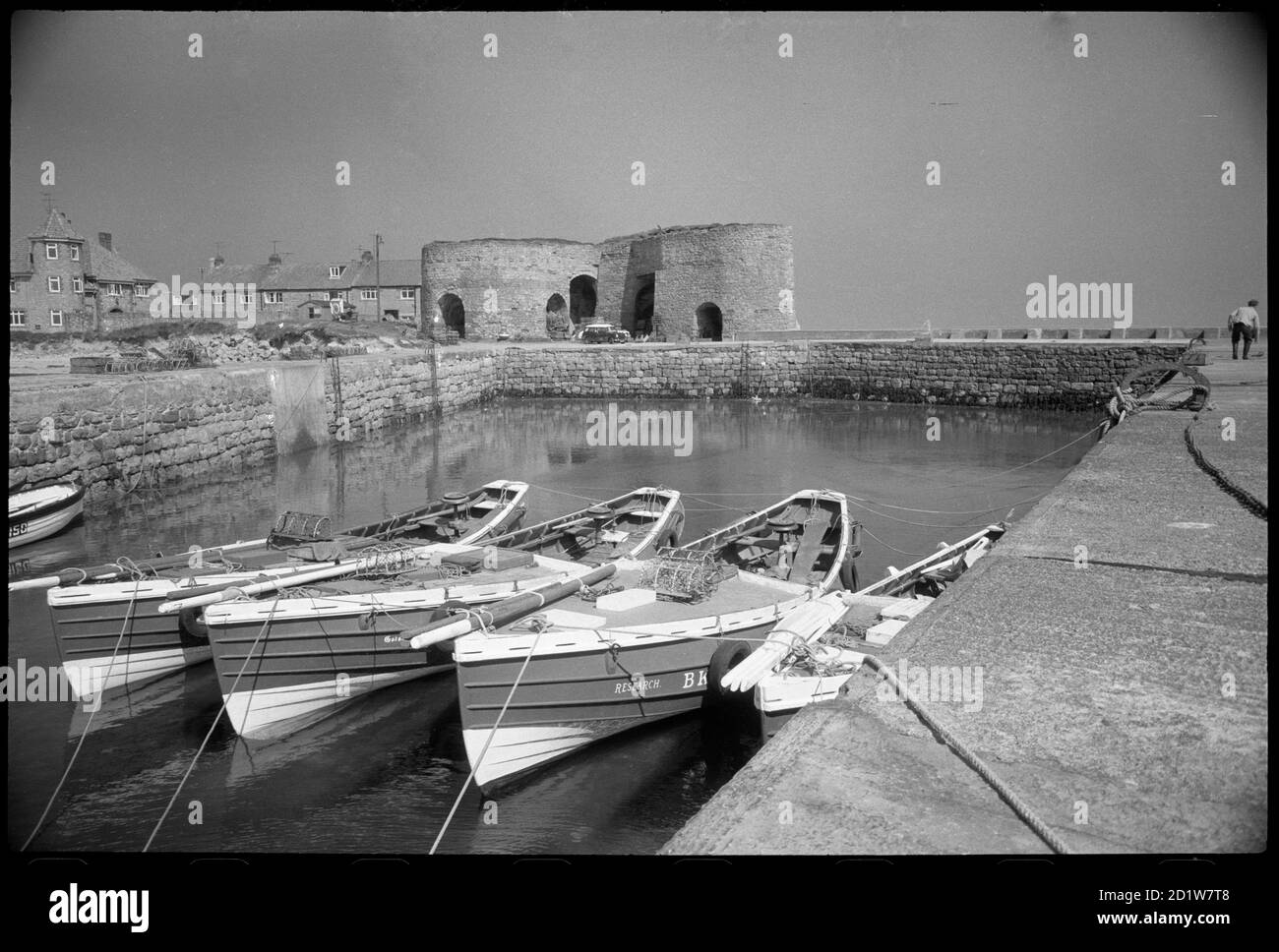 Eine allgemeine Ansicht von Beadnell Hafen, mit kleinen Booten im Vordergrund, und die Kalköfen im Hintergrund, Northumberland, UK. Stockfoto