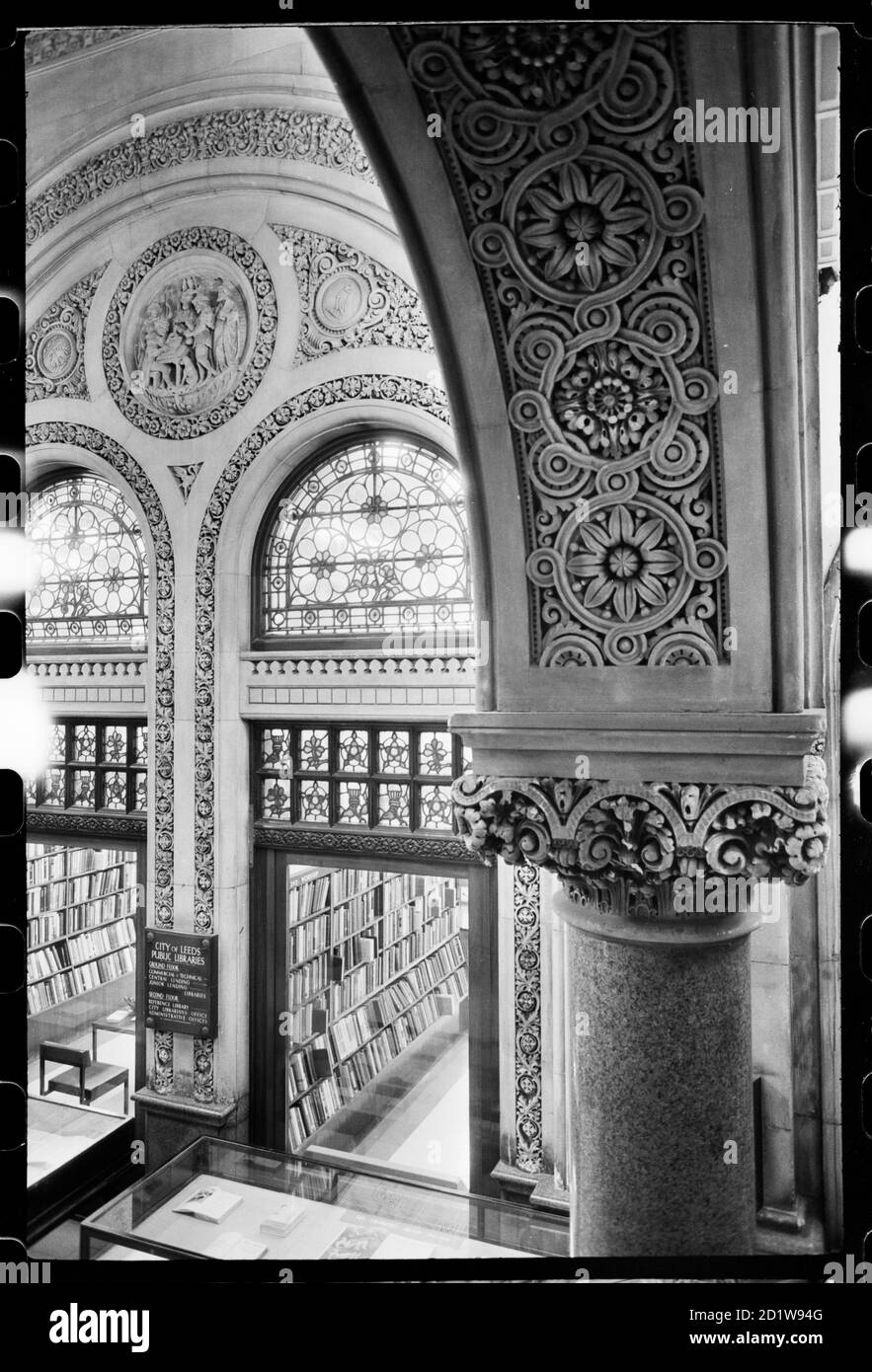 Interieur eines historischen Gebäudes, doppelbögiger Eingang zu einem Büchereiraum im Erdgeschoss, der die Unterseite eines kunstvoll geschnitzten Bogens zeigt Stockfoto