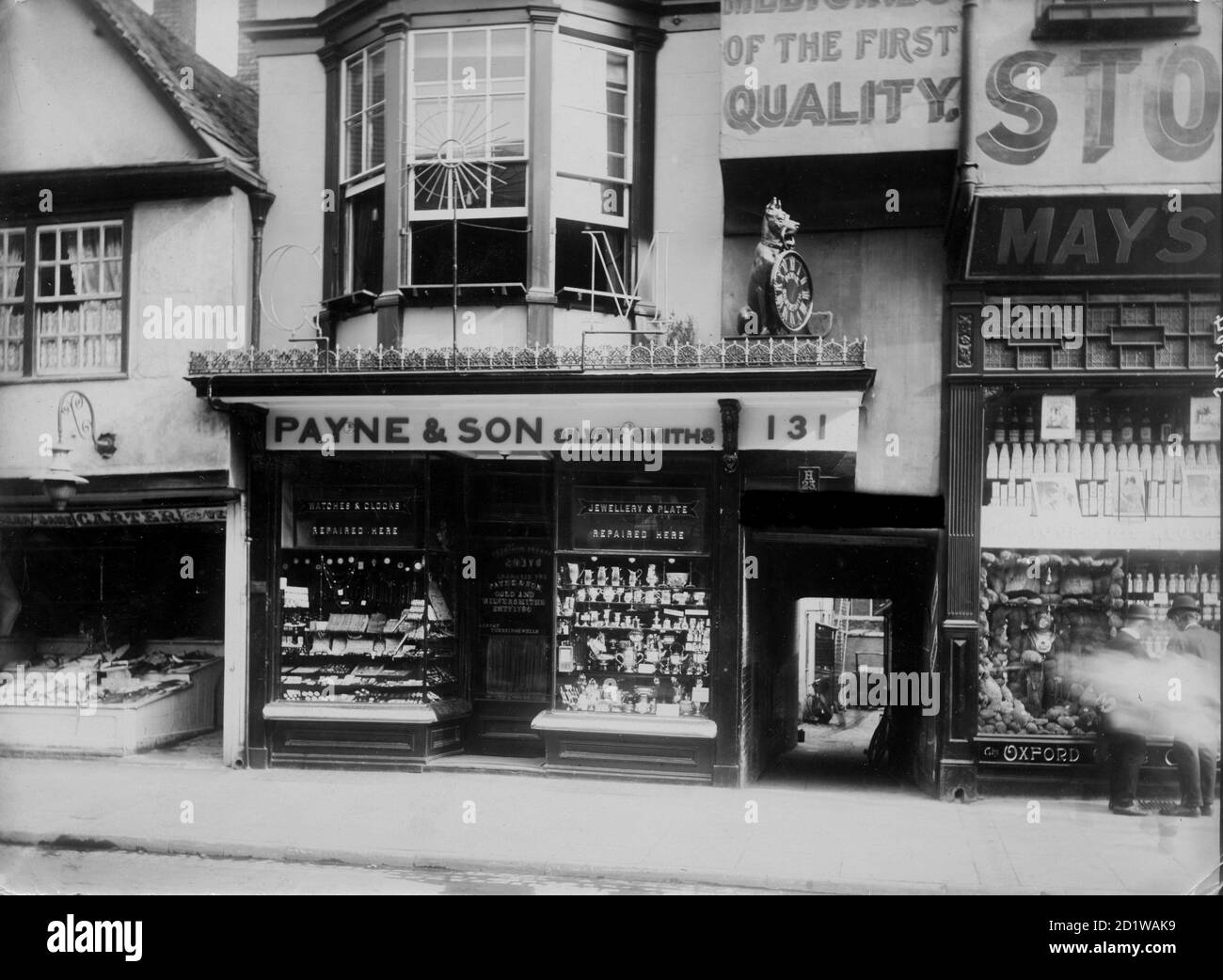 Payne Und Son, High Street, Oxford, Oxfordshire. Die Geschäftsräume von Payne und Son the Jewelers, die einen Hund zeigen, der eine Taschenuhr in seinem Mund über dem Eingang hält. Das Unternehmen handelt noch heute von diesem Laden aus. Stockfoto