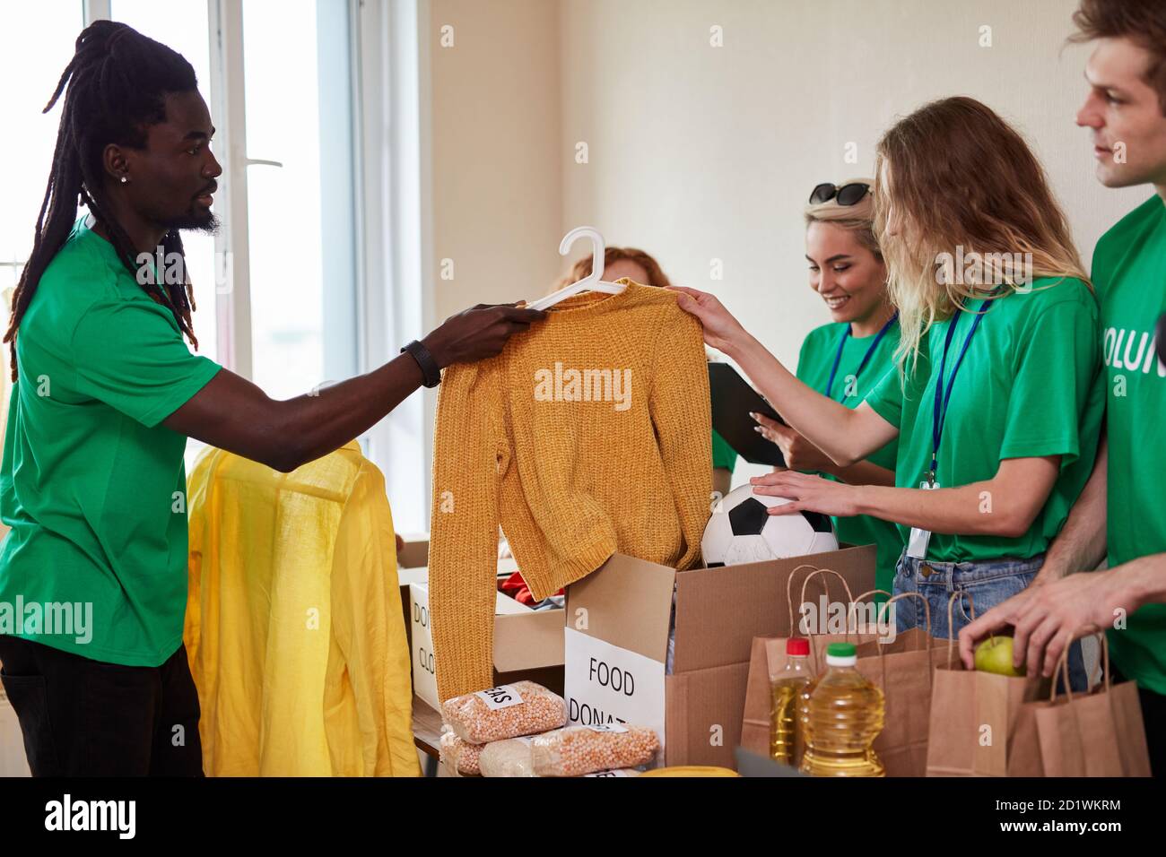 Junge multi-ethnische Gruppe von Menschen für Wohltätigkeitsorganisationen  versammelt, gutherzigen Männer und Frauen in grünen T-Shirt haben Kartons  mit Kleidung und Essen, wollen armen Menschen helfen Stockfotografie - Alamy
