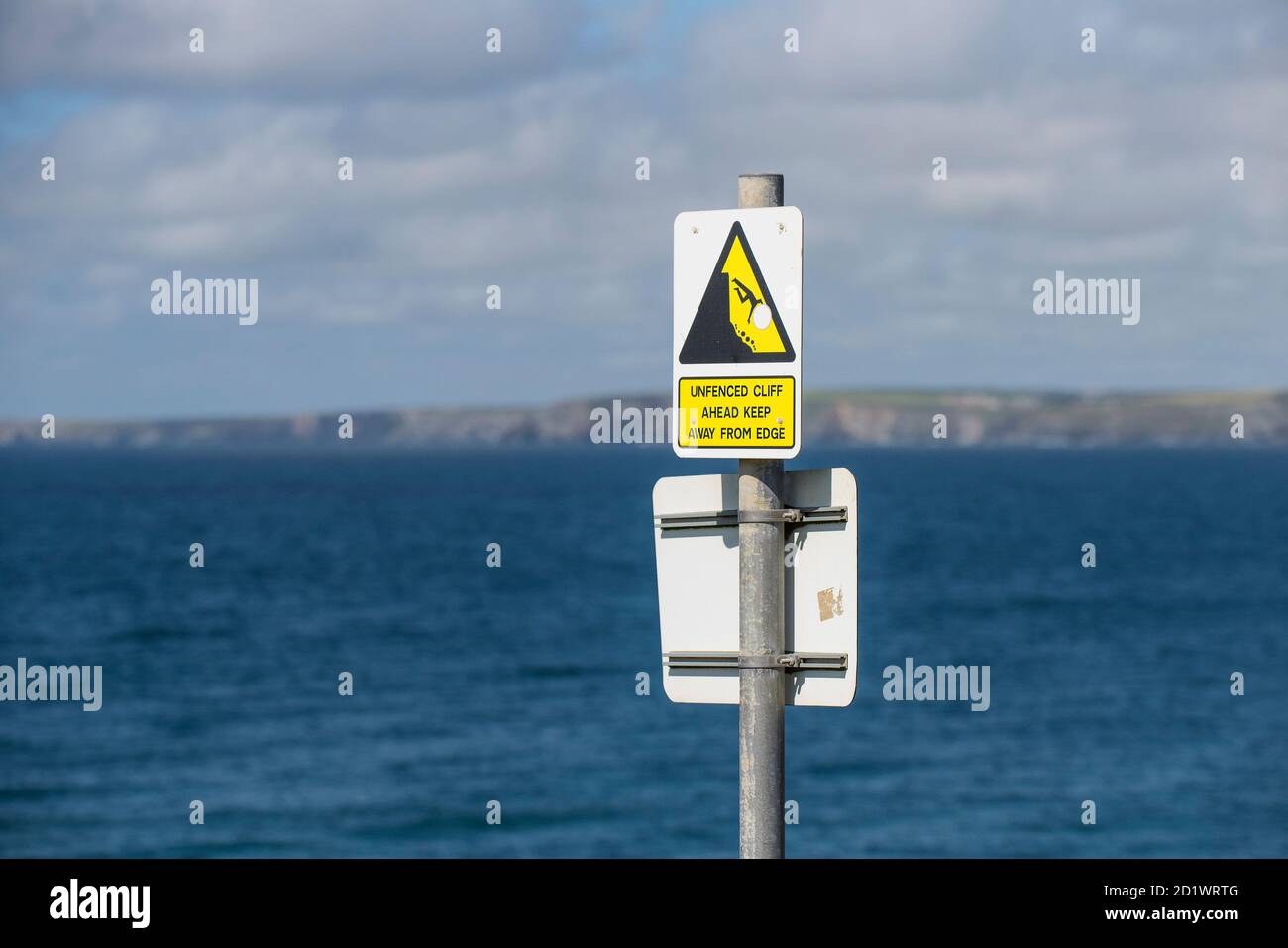 Ein Schild, das vor den Gefahren einer nicht eingezäunten Klippe an der Küste von newquay in Cornwall warnt. Stockfoto