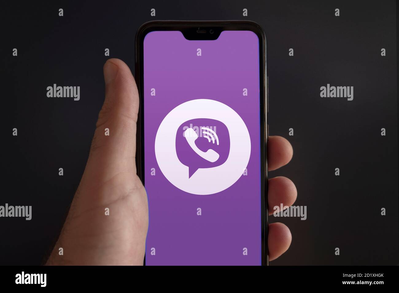 Der Bildschirm eines Smartphones von einer männlichen Hand gehalten Mit Viber Messenger Video Konferenz App Logo auf einem schwarzen Hintergrund Stockfoto