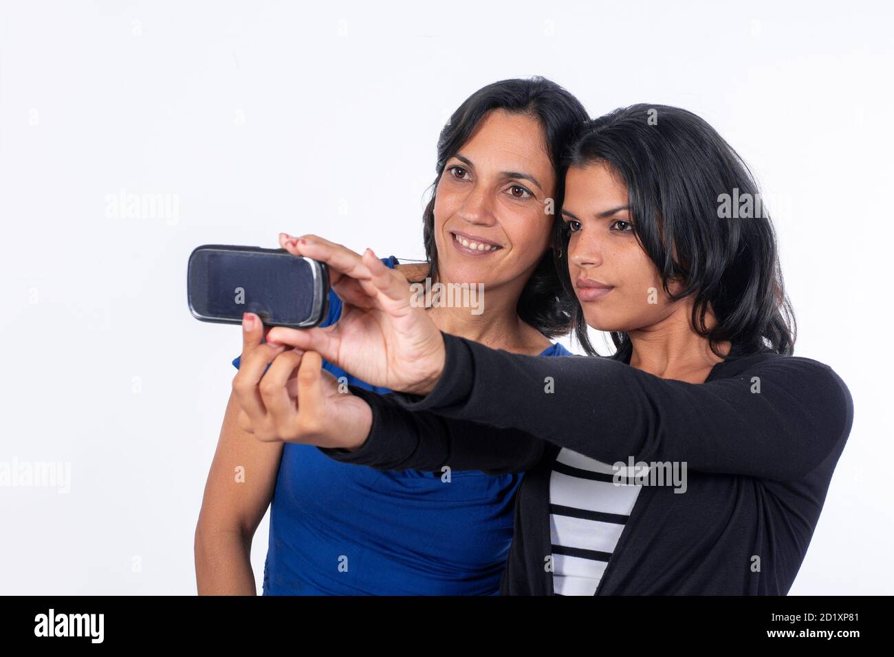 Eine Frau und ein Mädchen nehmen ein Selfie mit einem Handy. Beide haben schwarze Haare Stockfoto