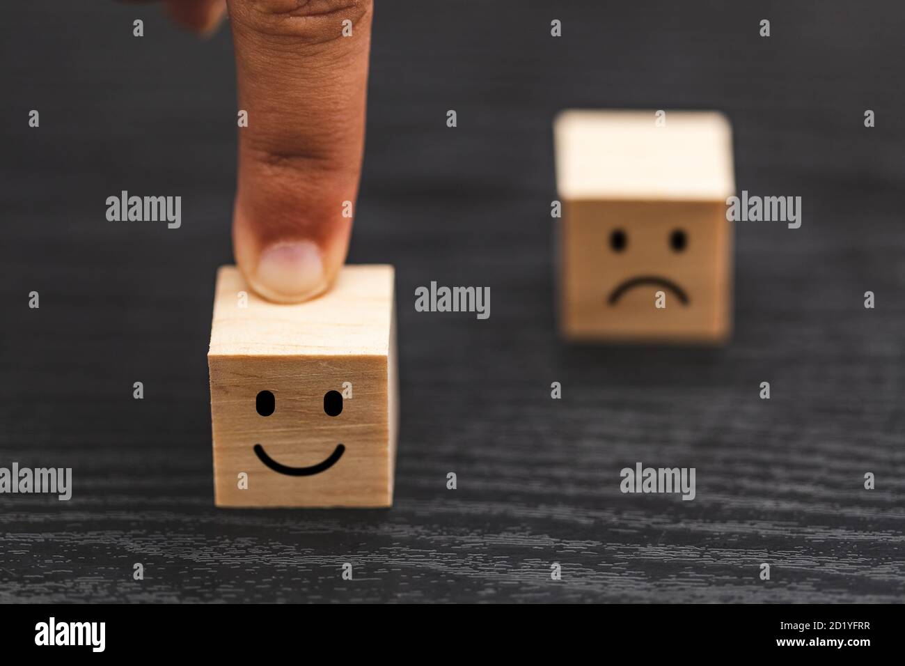 Hand wählen Smiley Gesicht und verschwommen traurig Gesicht Symbol auf Holz Würfel, Service-Bewertung, Zufriedenheit Konzept. Stockfoto