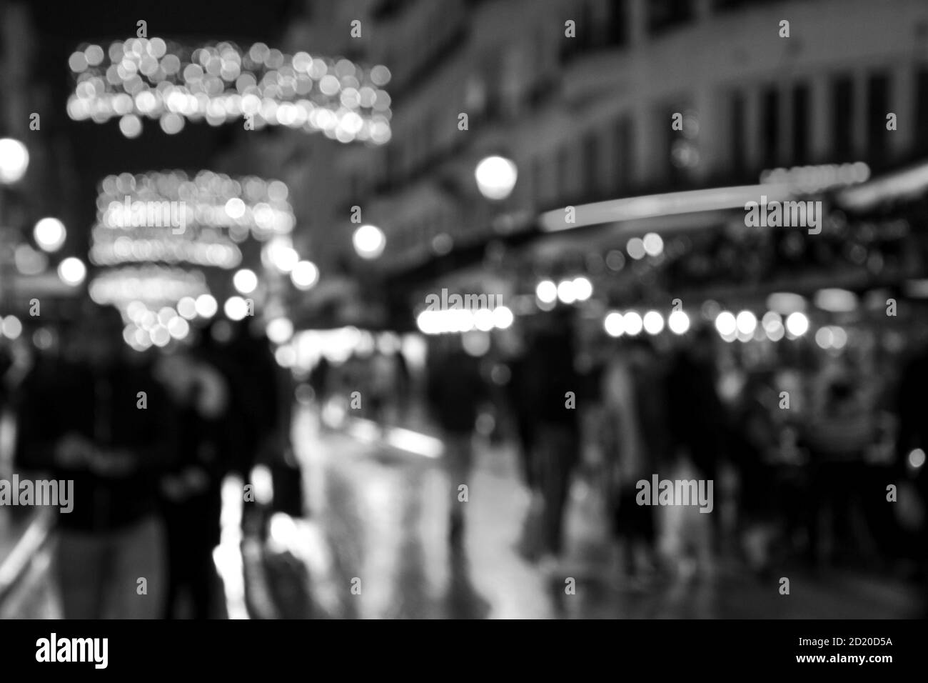 Verschwommenes Foto von Montorgueil Straße in Paris bei Nacht mit schönen Weihnachtsbeleuchtung Dekoration und Menschen Menge. Reisen im Winter. Schwarz weiß Stockfoto