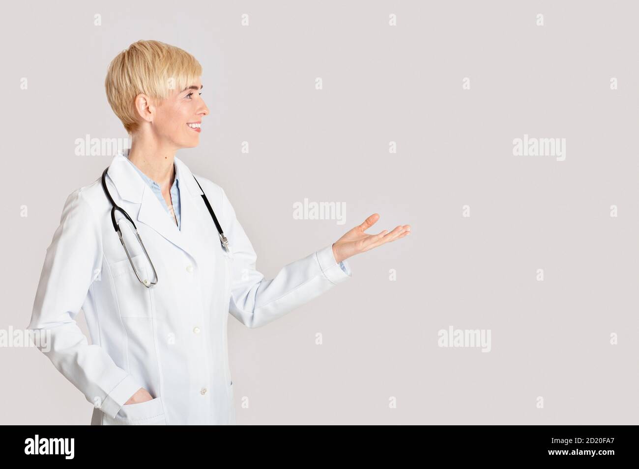Gesundheitswesen, medizinische Fachkräfte und Arztbesuch. Freundliche weibliche Punkte mit der Hand auf leerem Raum Stockfoto