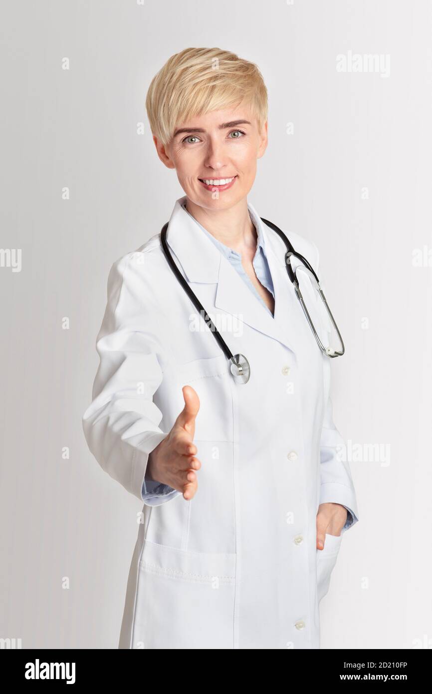 Besuch beim Hausarzt oder Therapeuten. Freundliche Erwachsene Frau hält die Hand für die Begrüßung der Patientin in der Klinik Stockfoto