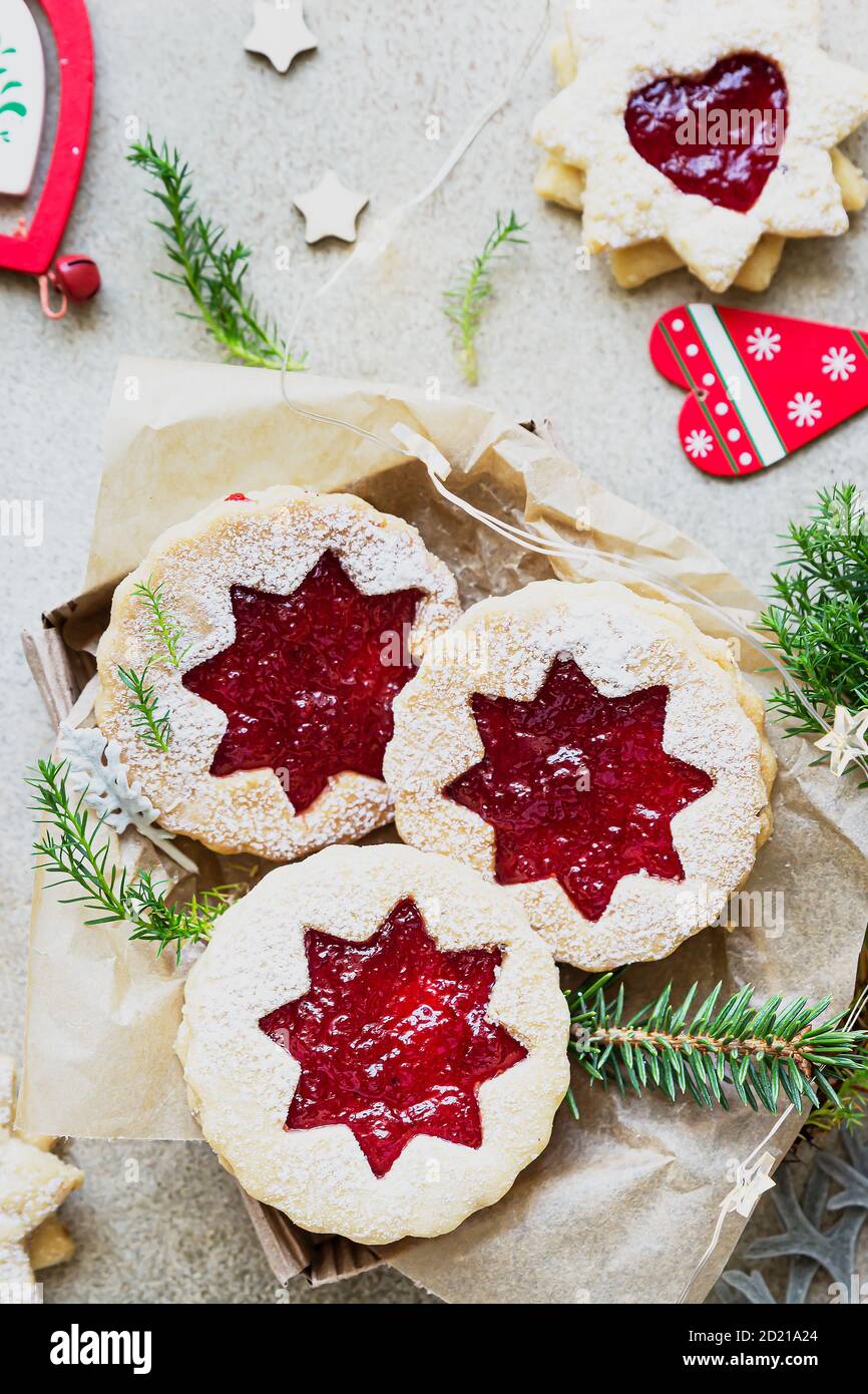 Traditionelle österreichische Kekse mit roter Marmelade. Weihnachten oder Neujahr hausgemachte süße Geschenk in Geschenkbox. Festliche Dekoration. Steinhintergrund. Draufsicht. Stockfoto