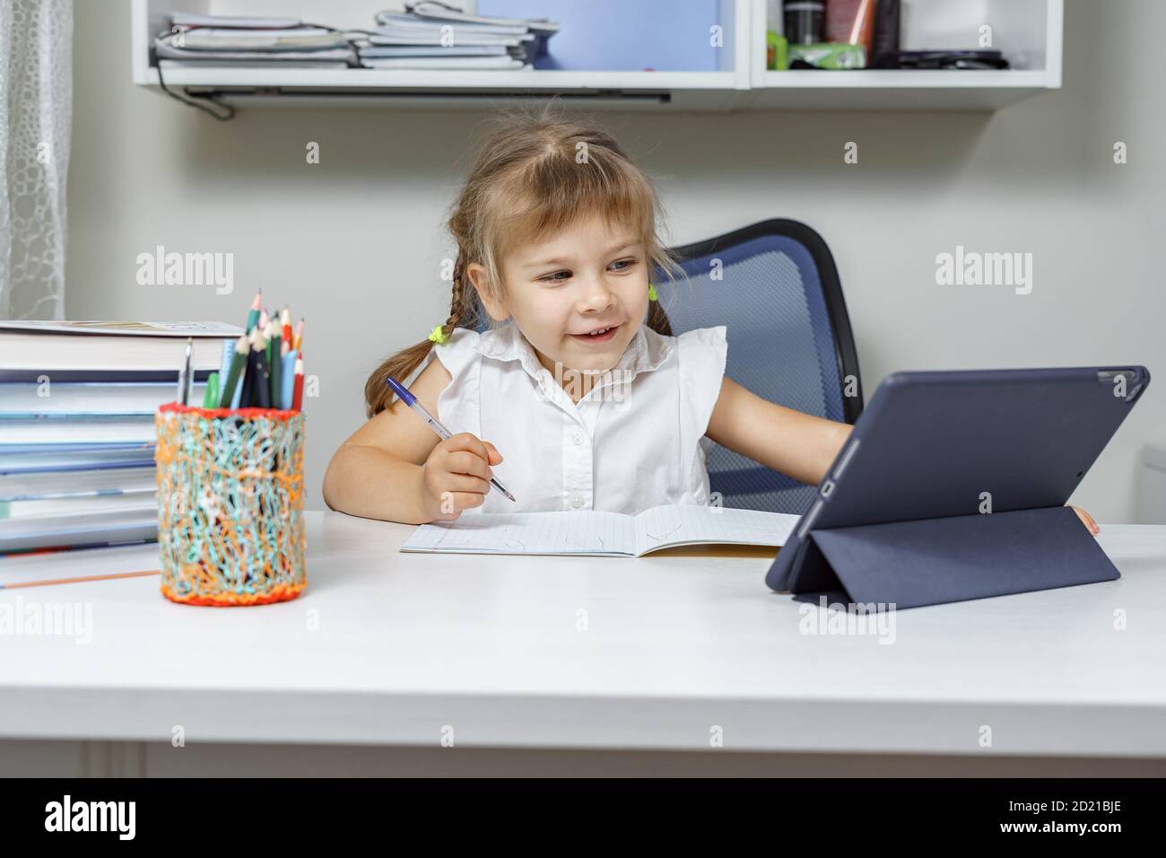 Kleines Mädchen auf einem entfernten Online-Unterricht mit einem Lehrer. Fernunterricht während der COVID-19 Pandemie Stockfoto