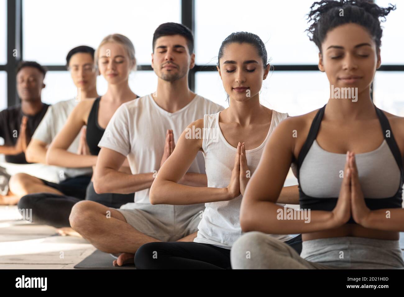 Geist-Harmonie. Gruppe junger sportlicher Yoga-Liebhaber, die gemeinsam im Studio meditieren Stockfoto