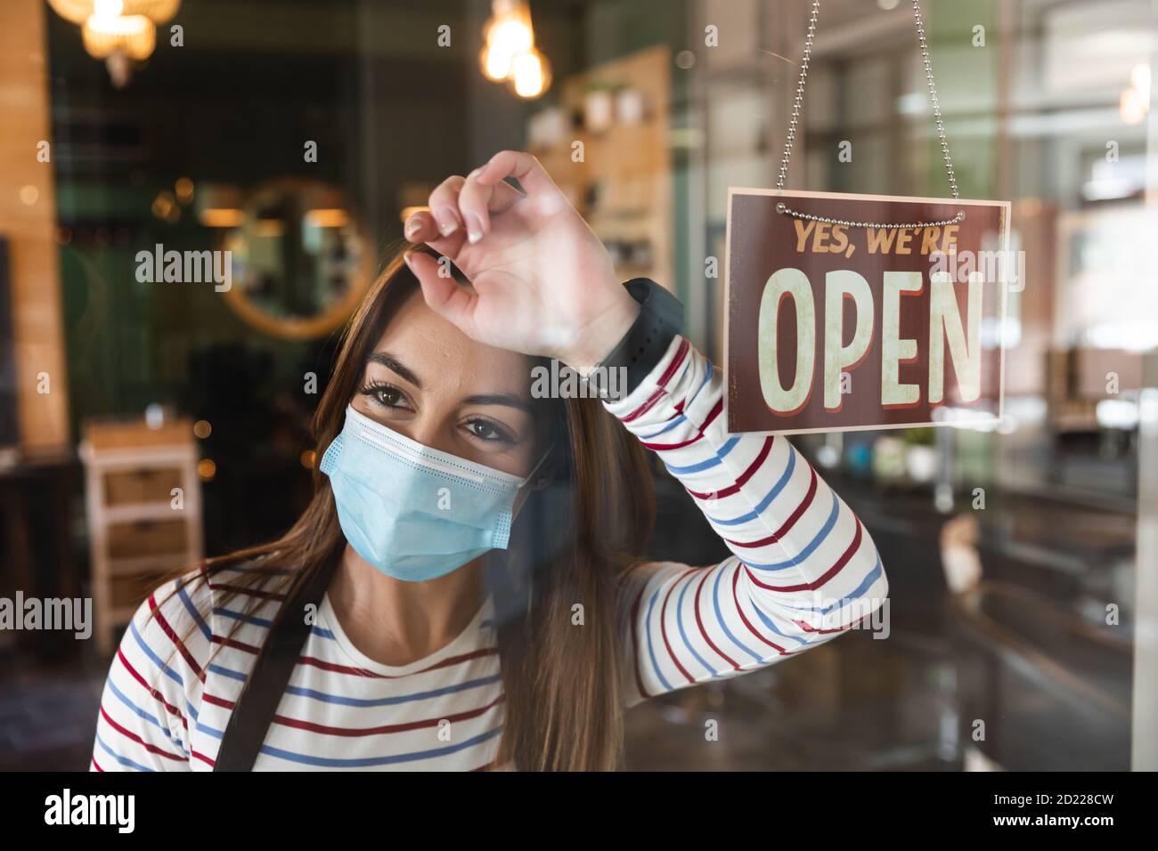 Weibliche Friseur trägt Gesichtsmaske auf dem Glas lehnt Friseursalon Stockfoto