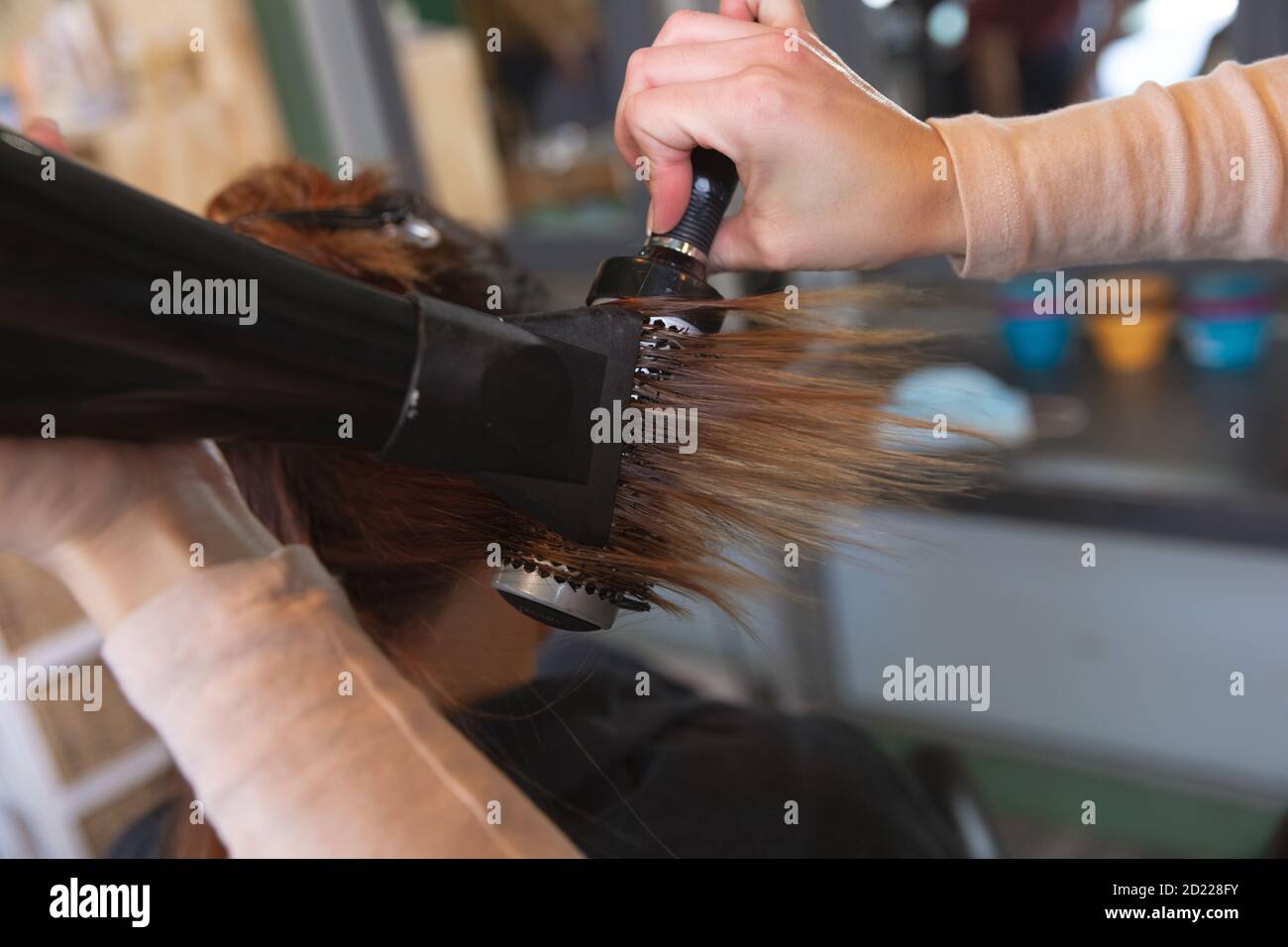 Mitte Abschnitt der weiblichen Friseur Föhnen Haar der Frau Kunde im Friseursalon Stockfoto