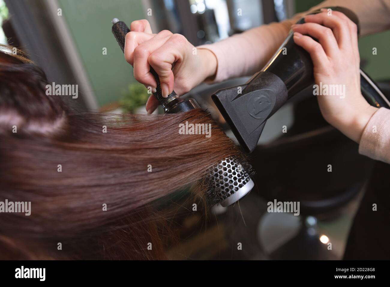 Mitte Abschnitt der weiblichen Friseur Föhnen Haar der Frau Kunde im Friseursalon Stockfoto