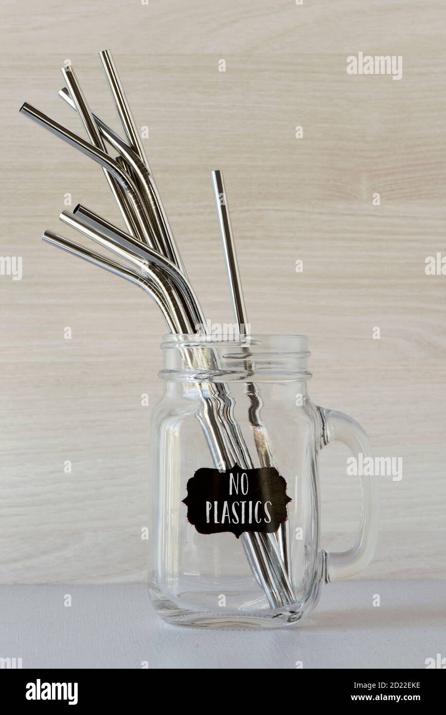 Einige wiederverwendbare Trinkhalme aus Metall mit verschiedenen Formen und Längen in einem handhabbaren Glas, und der Text keine Kunststoffe in einem Etikett angebracht Stockfoto