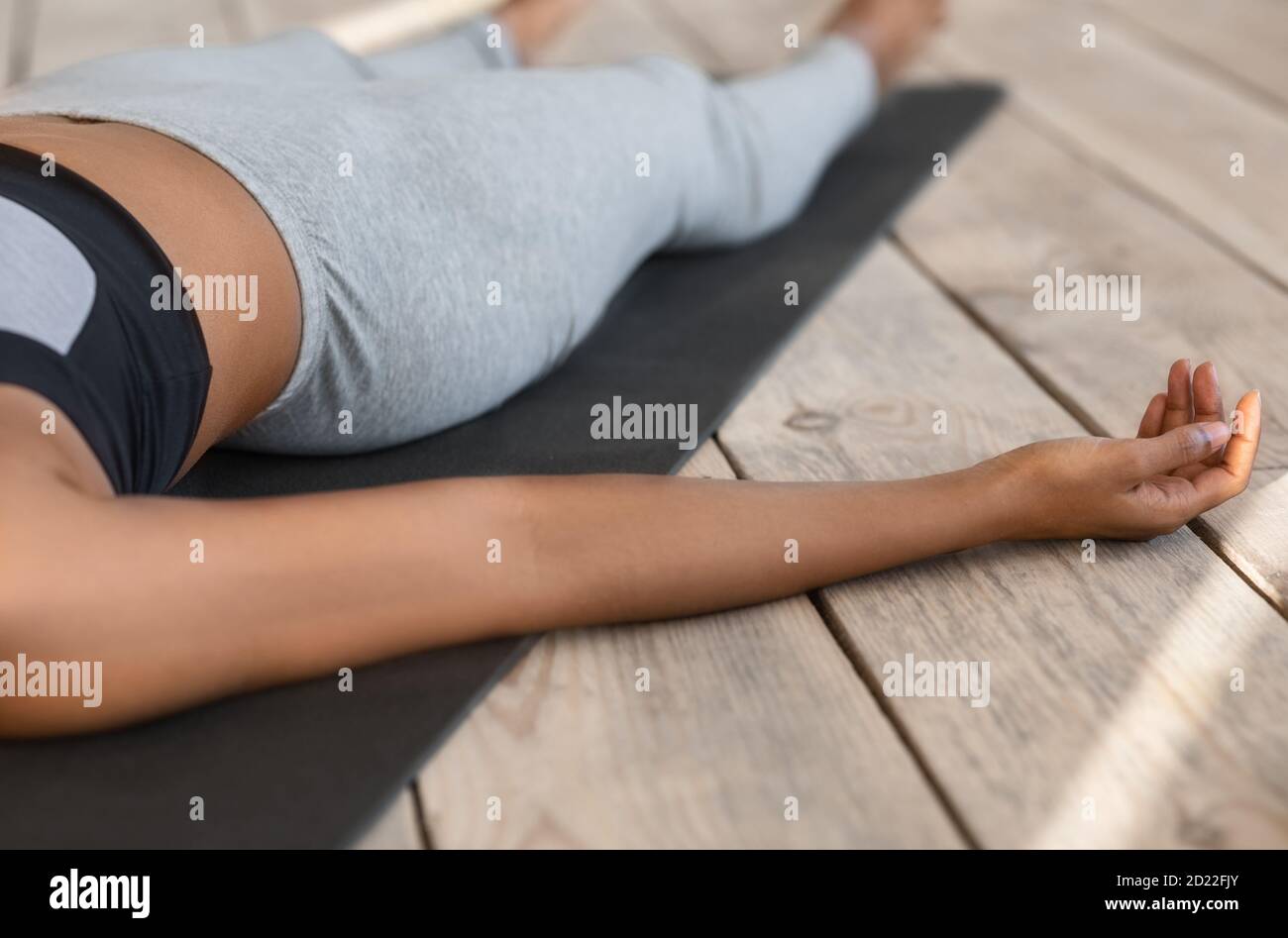 Nicht erkennbare afrikanische Frau liegt auf Yoga-Matte in Leiche Pose, zugeschnittenes Bild Stockfoto