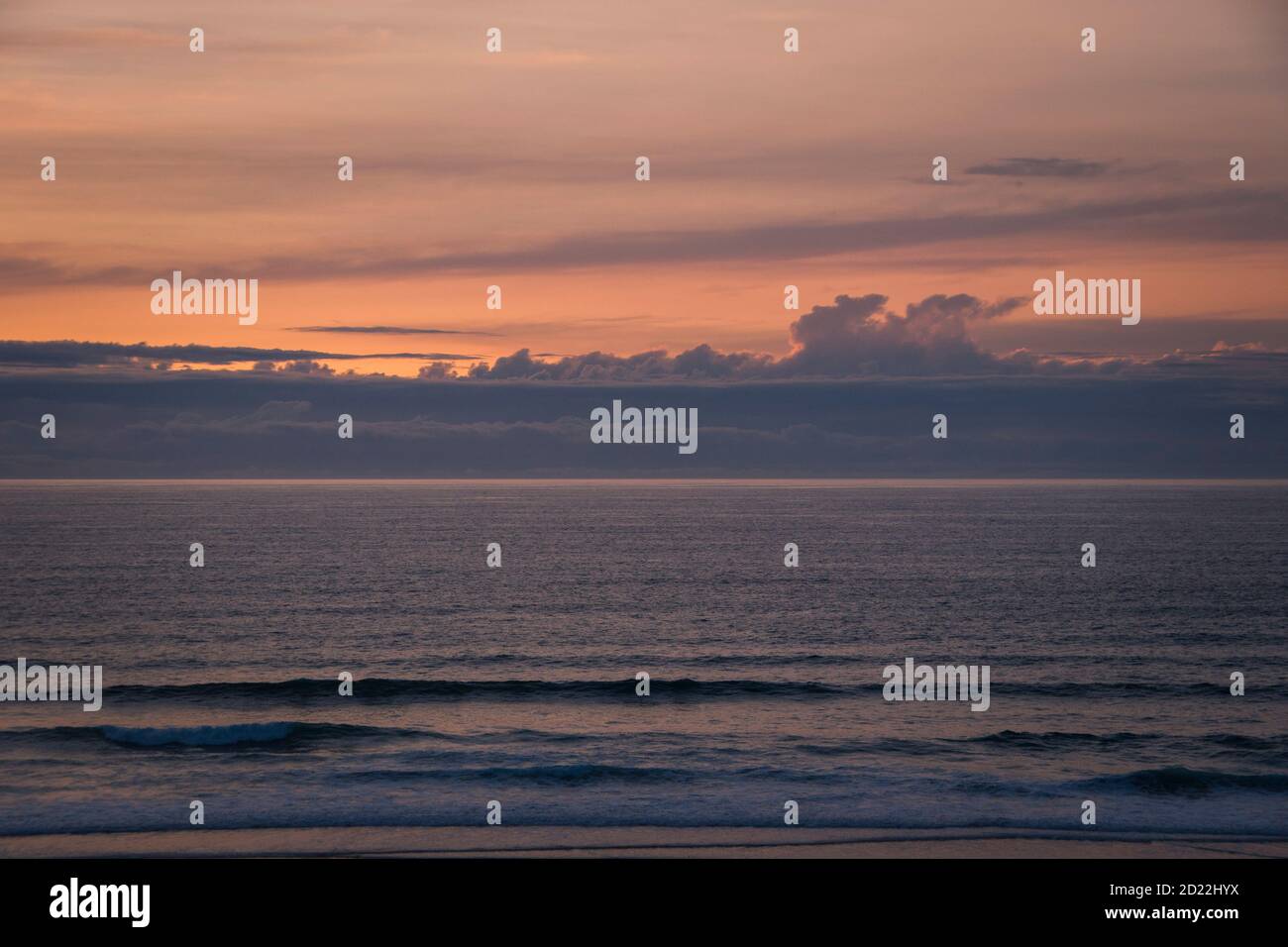 Ozeanlandschaft bei Sonnenuntergang, nachdem die Sonne verschwindet, mit rosa Tönen, mit der Horizontlinie, die den bewölkten Himmel und das Wasser trennt Stockfoto