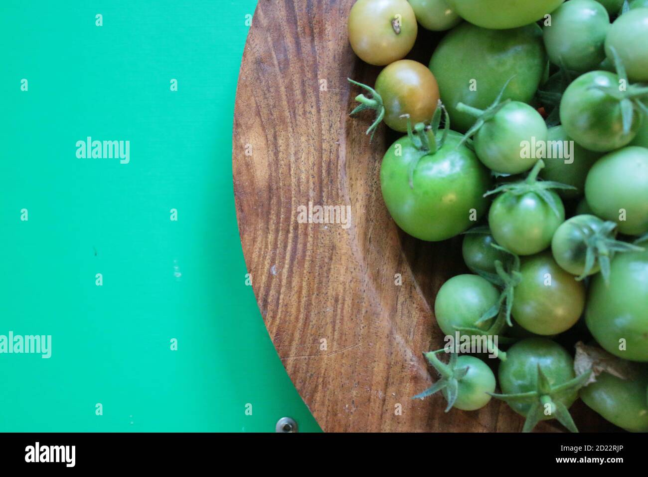 Nahaufnahme Tomaten, frische reife saftige Früchte aus Bio-Garten in Holz Handwerk Schale Innenaufnahme vor lebendigen grünen Kontrast Hintergrund geerntet Stockfoto