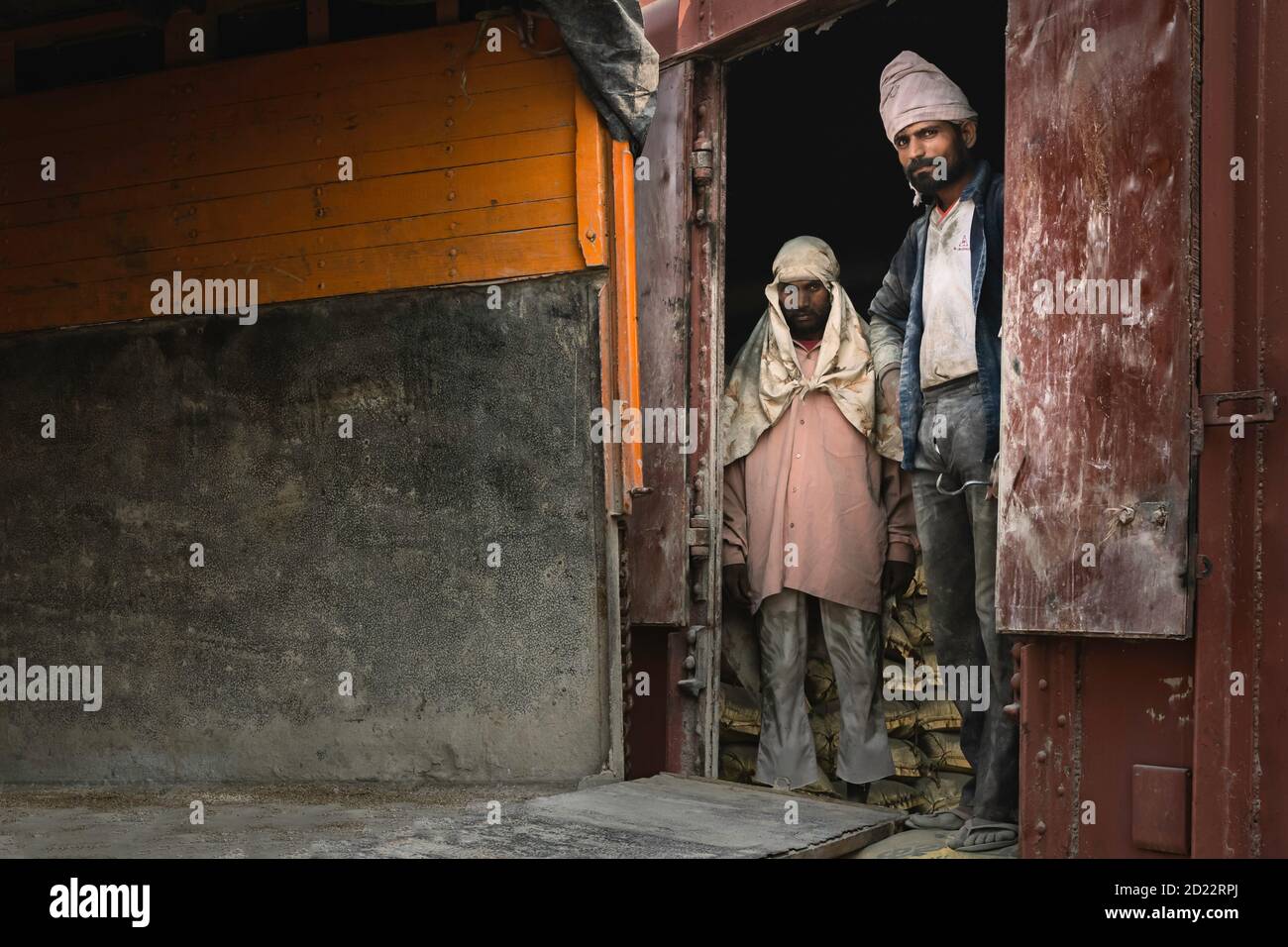 Porträt von Männern, die nur Kopftuch als Schutz trugen, um Zementsäcke von Zug zu Lkw in Mathura, Uttar Pradesh, Indien zu bewegen. Stockfoto