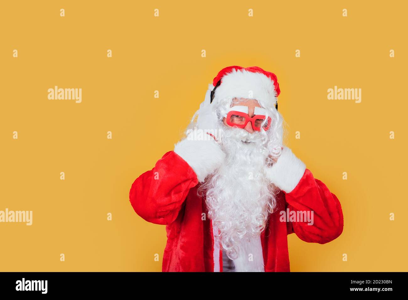 Moderner Weihnachtsmann, der Musik mit Kopfhörern lauscht Stockfoto
