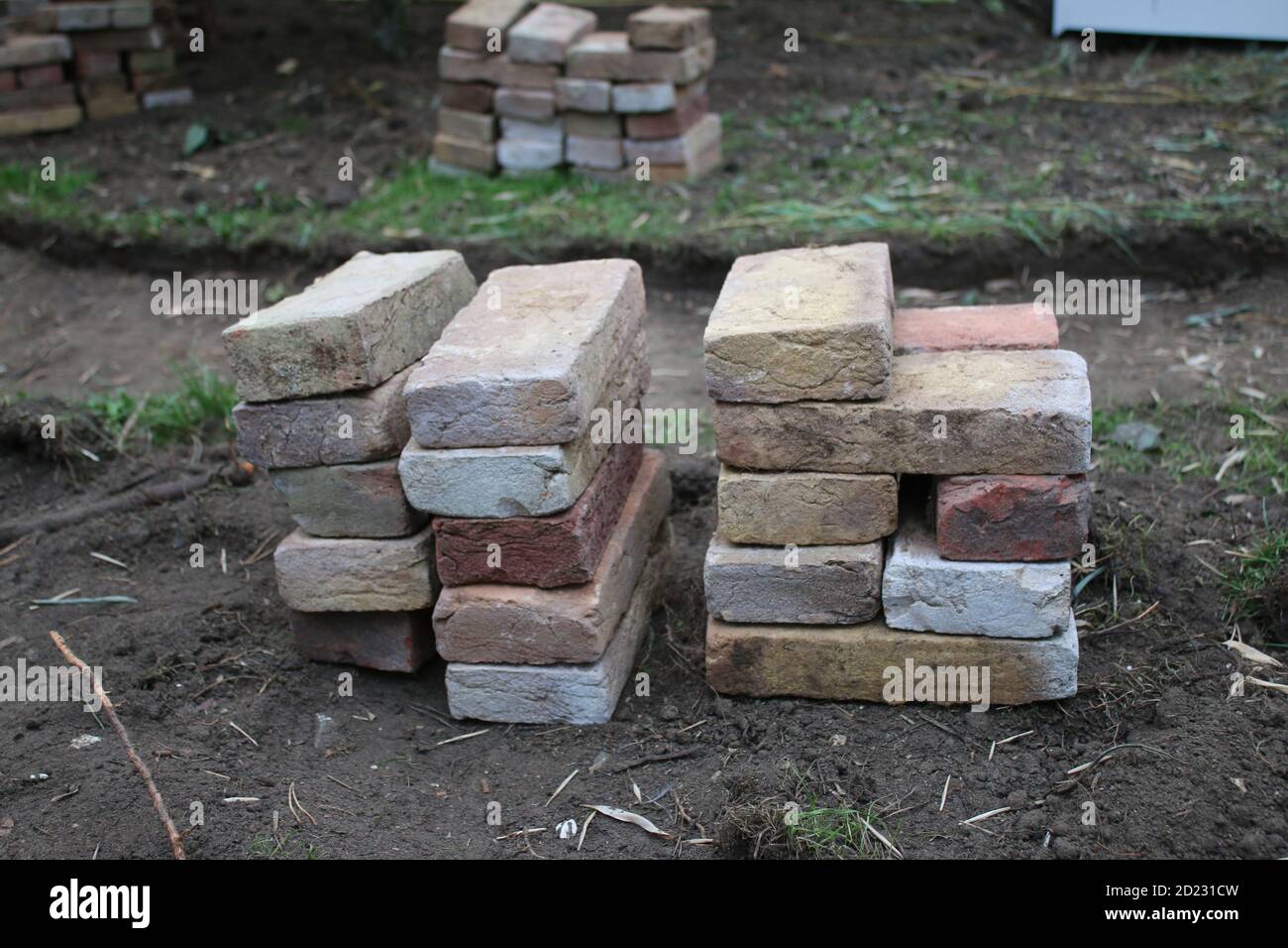 Nahaufnahme des Stapels von alten Lehm zurückgewonnenen Ziegel, jedes längliche Rechteck von Hand gefertigt und aus dem Gebäude zu wiederverwenden, um Gartenweg durch Rasen zu legen gerettet Stockfoto