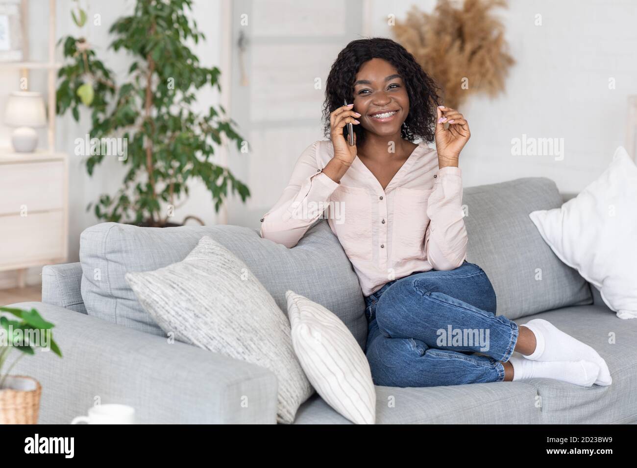 Fröhliche Afrikanische Dame Mit Telefonanruf Beim Entspannen Auf Der Couch Zu Hause Stockfoto