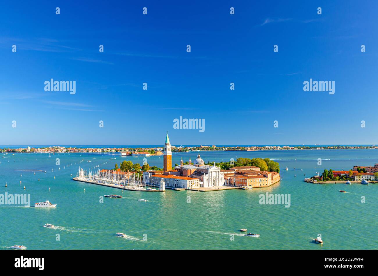 Luftpanorama der Insel San Giorgio Maggiore mit Campanile San Giorgio in der Lagune von Venedig, Segelboote im Markusbecken, Lido Insel, blauer Himmel Hintergrund, Venedig Stadt, Venetien Region, Italien Stockfoto