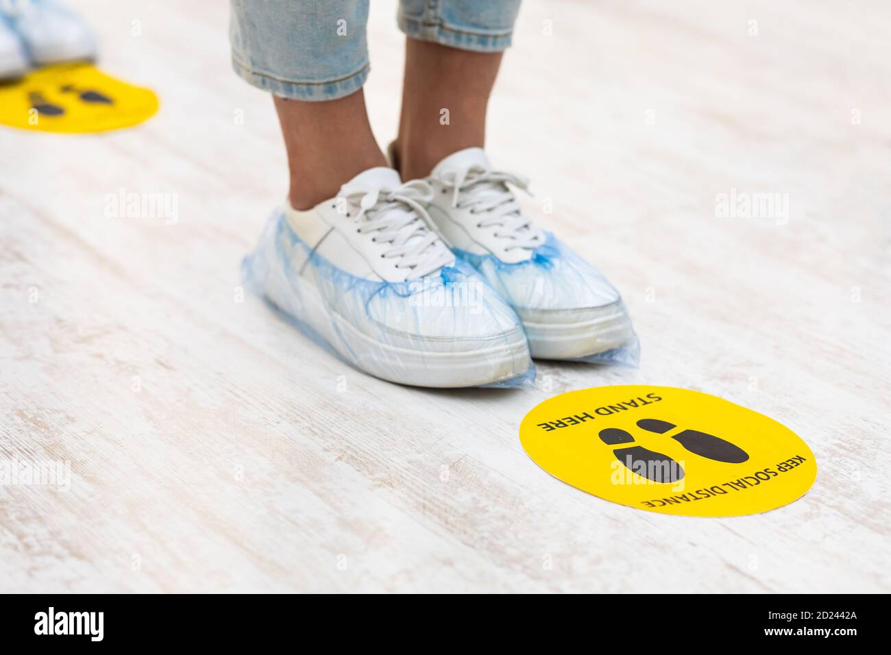 Mädchen Füße stehen in der Nähe von Social Distanzing Warnschild Innen Stockfoto