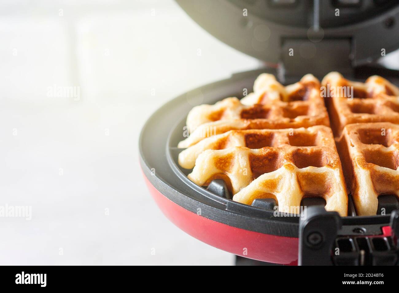 Der Prozess der Herstellung von hausgemachten Waffeln. Frisch gebackene Waffeln in einem Waffeleisen. Stockfoto