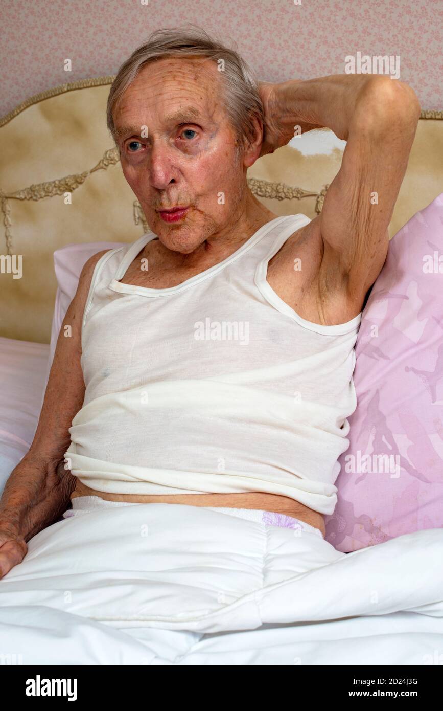 Älterer Mann pfeift sich im Bett Stockfoto